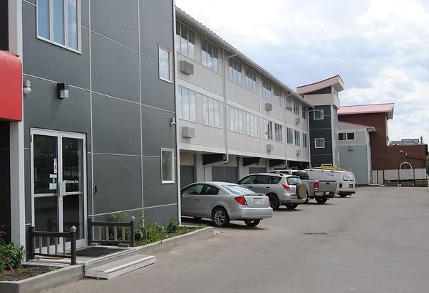 The exterior of Economy Inn Edmonton features guest parking beside a modern multi-storey building.