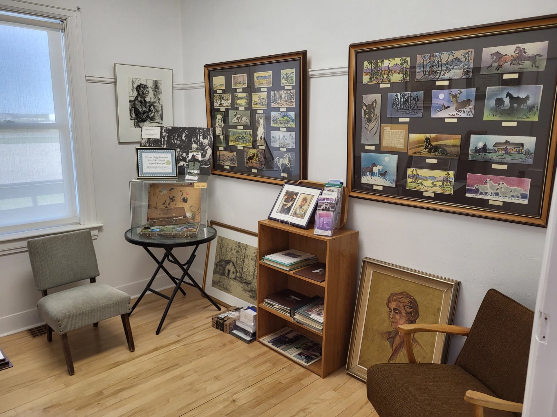 Gallery room with framed artwork, display panels, and bookshelves along the walls.