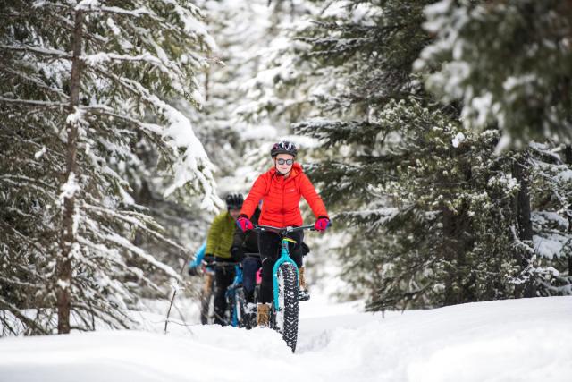 People fatbiking on a snowy trail through the trees in Castle Provincial Park