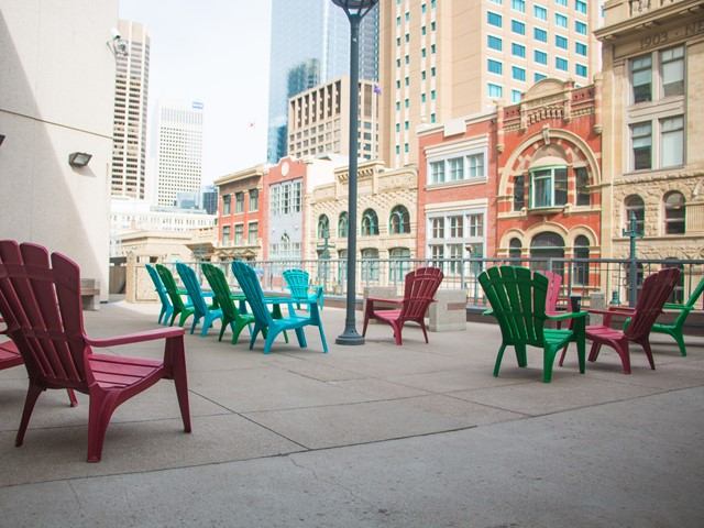 Colorful chairs outside the TELUS Convention Centre, with city buildings in the background.
