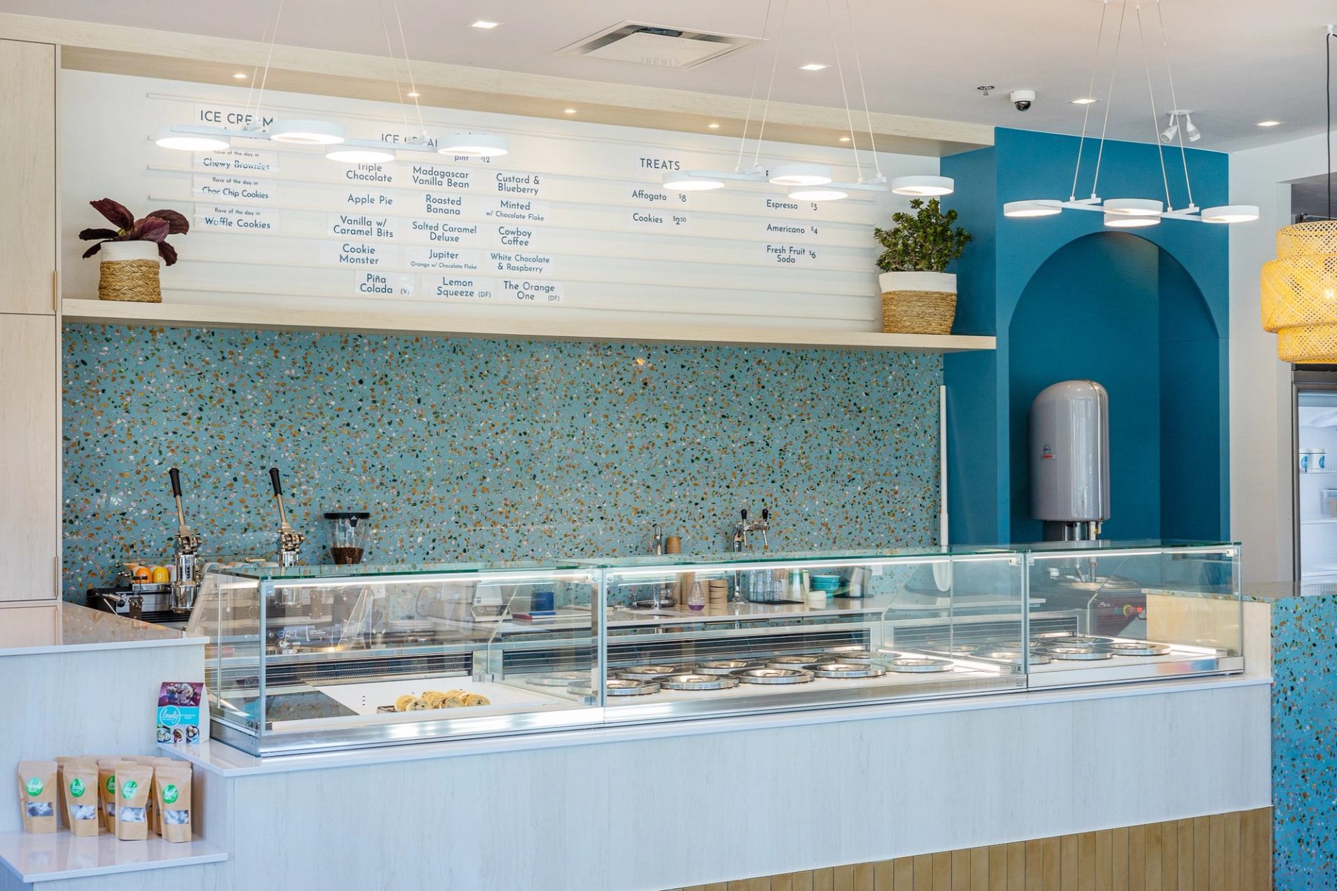 A modern ice cream shop counter showcasing a variety of ice cream flavors and toppings behind a glass display.
