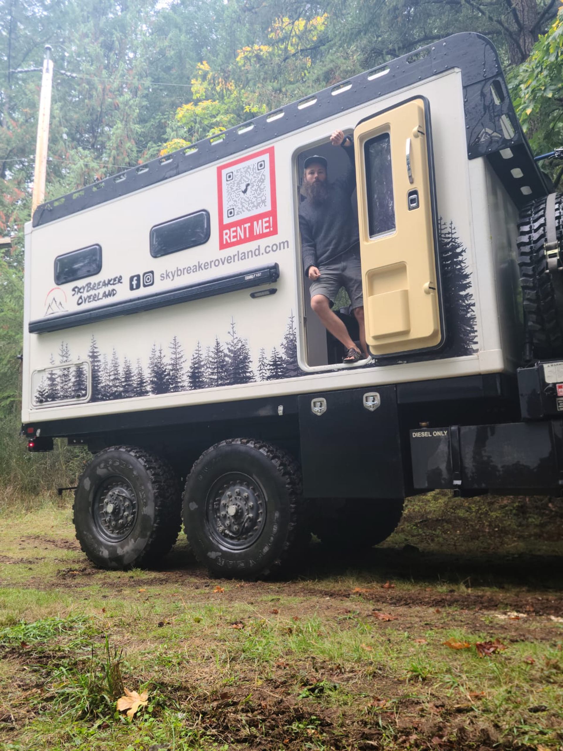 Truck with forest design, open door, and person standing in doorway.