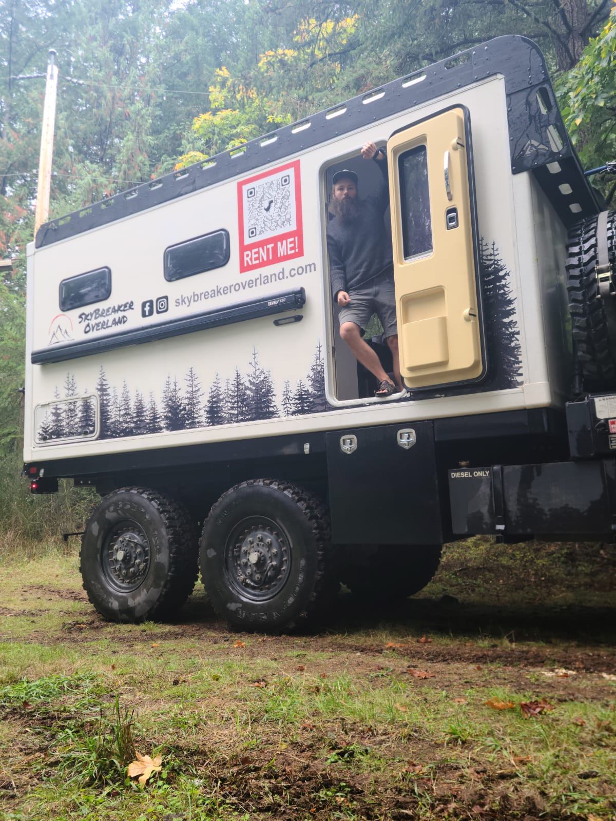 Truck with forest design, open door, and person standing in doorway.