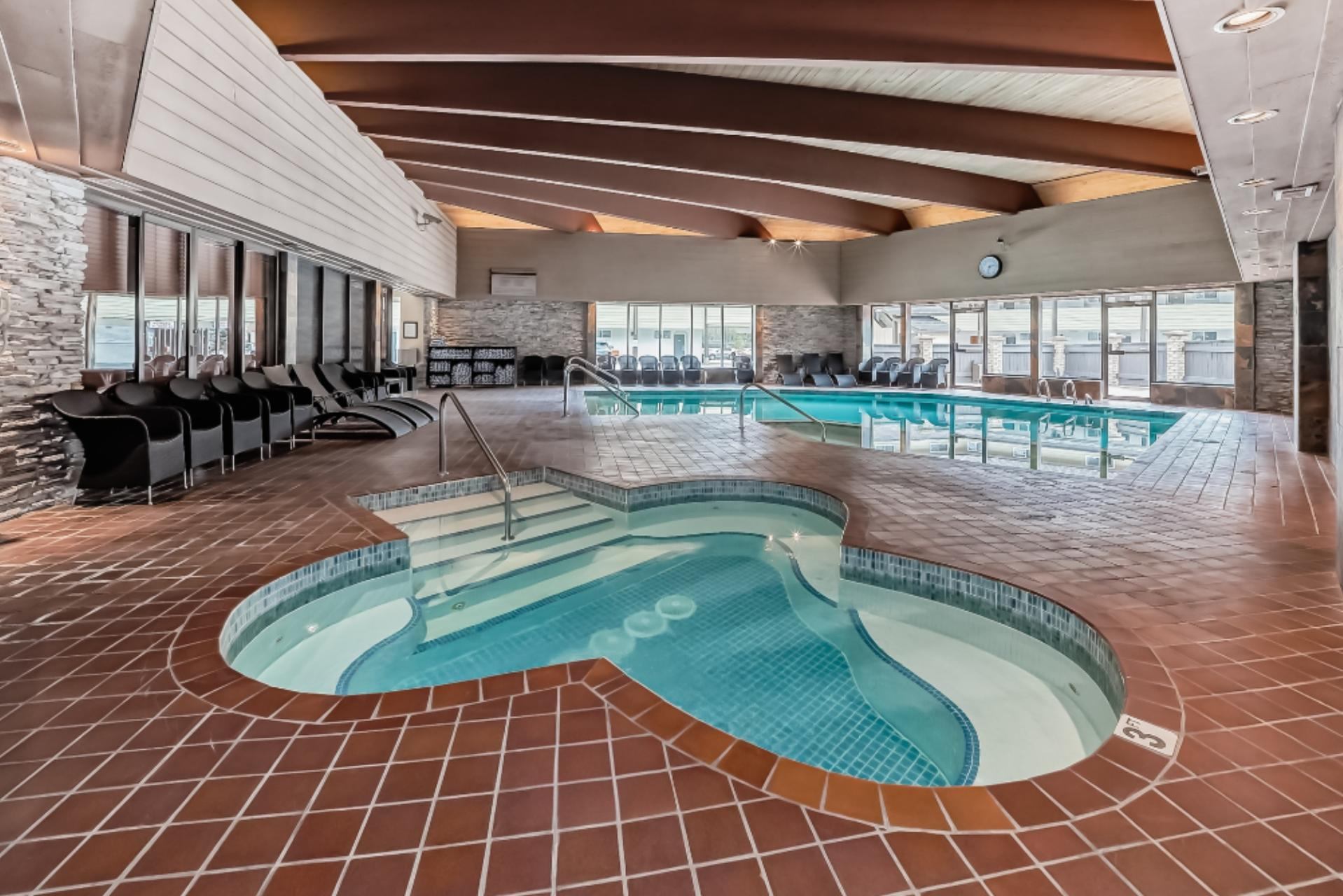 Spacious indoor pool area with a heart-shaped hot tub and lounge chairs along the wall