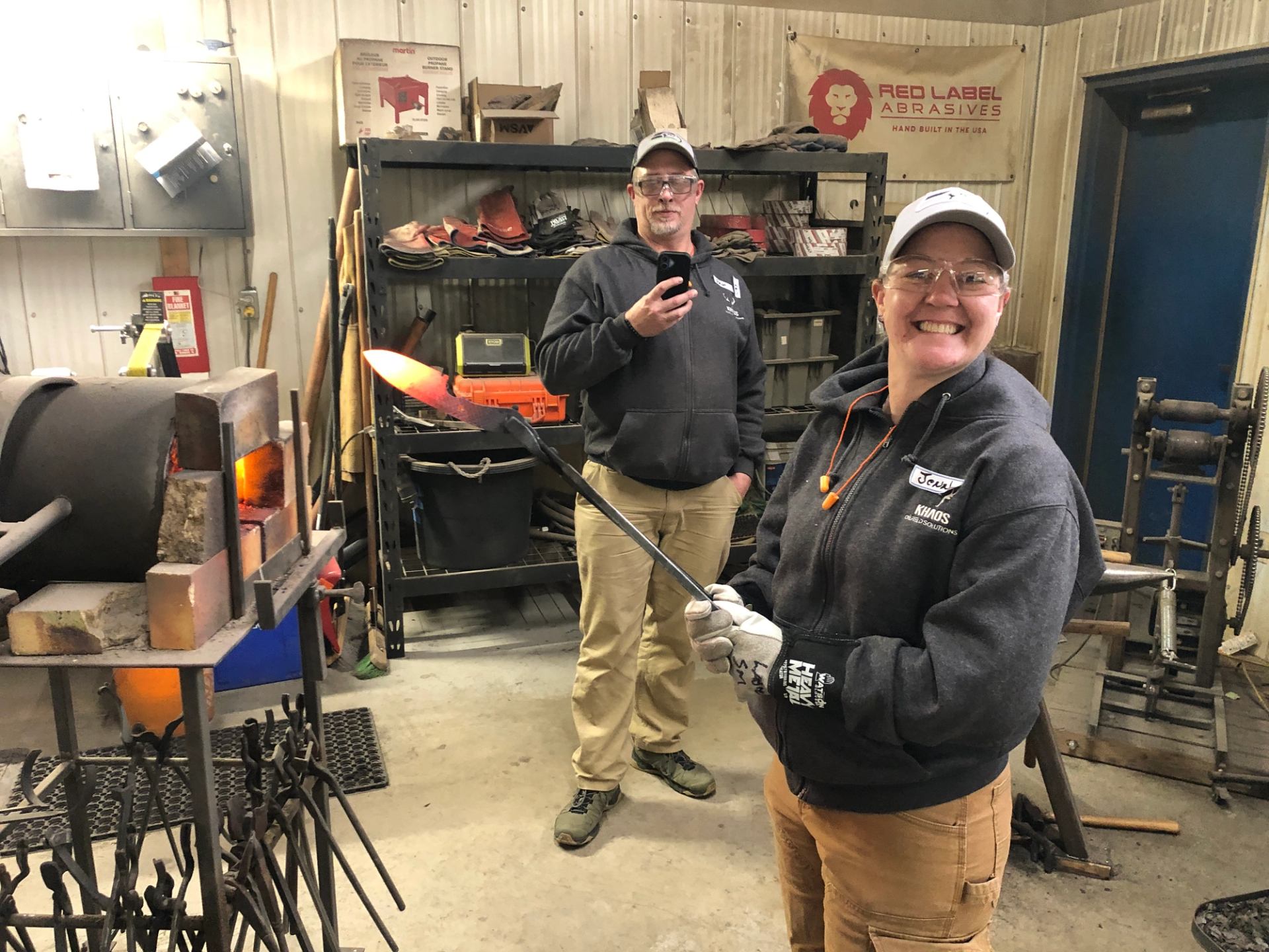 Participant holding heated steel beside a forge during a knife making class. 