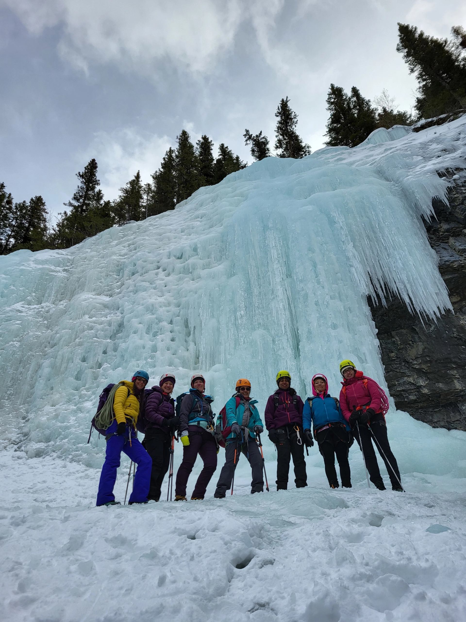Group in winter gear at base of massive frozen waterfall.