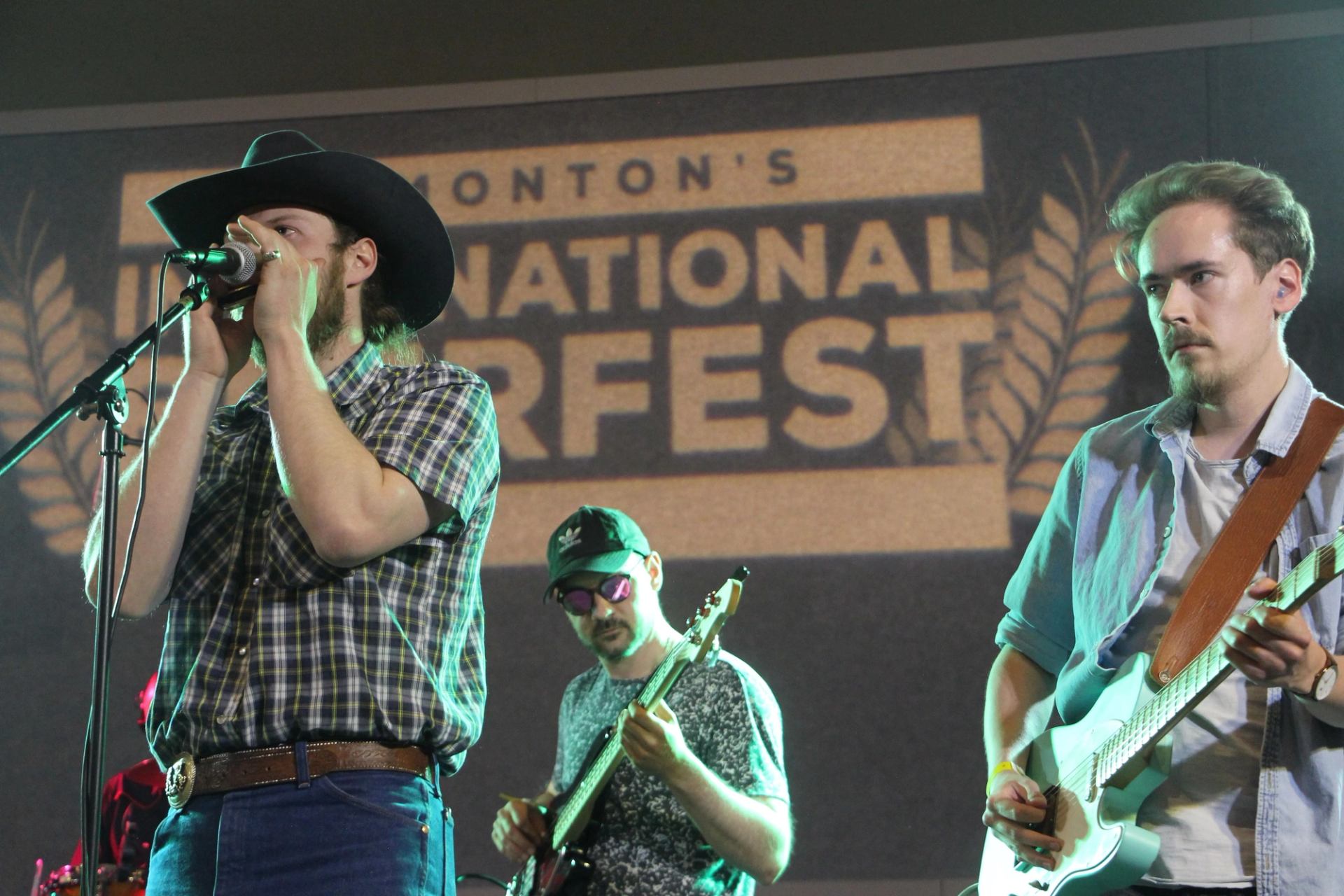 Country band performs on stage at Edmonton’s International Beerfest with guitars and microphone.