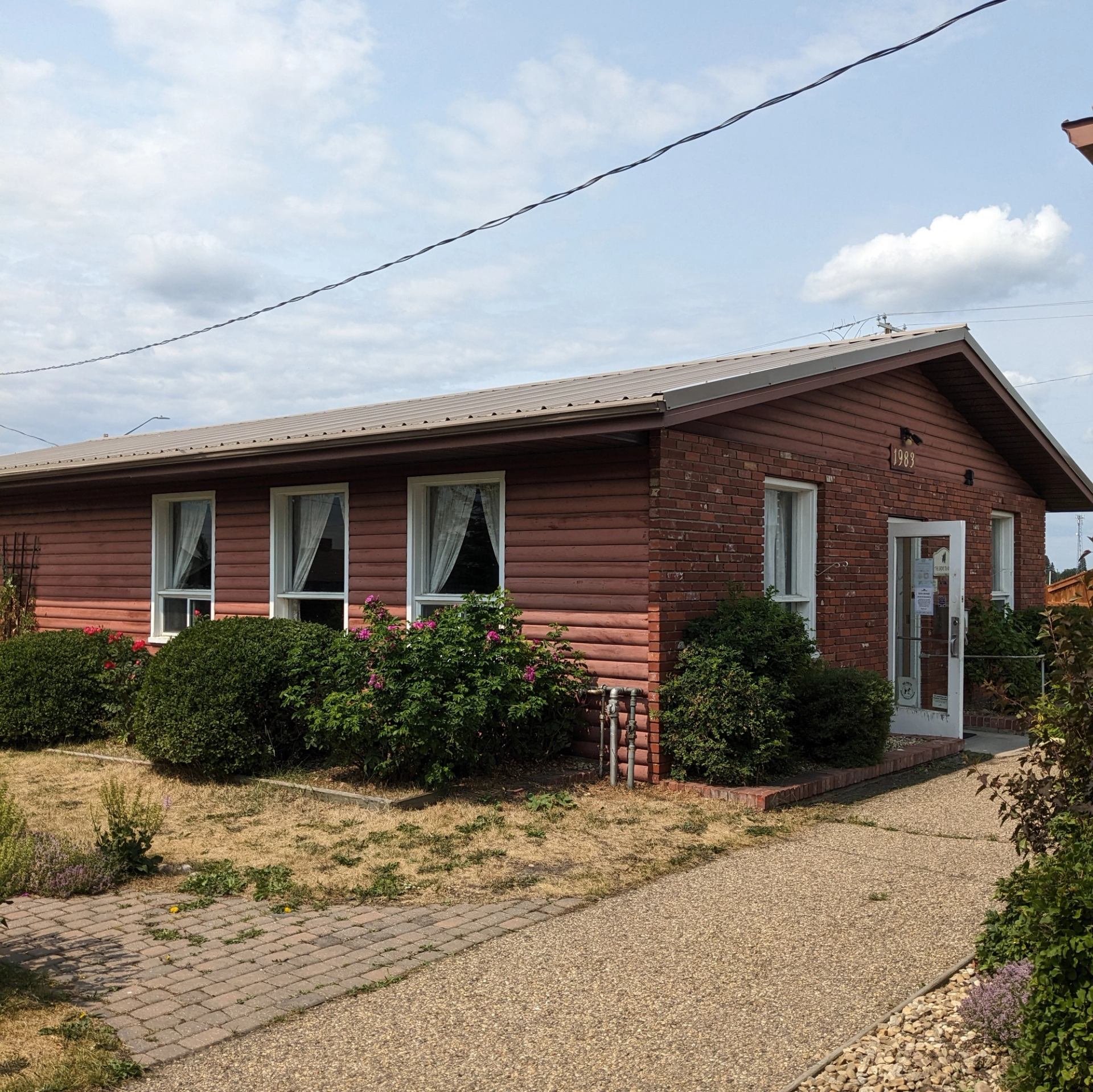 Red-brick tea room with white windows and gable roof in a rural setting.