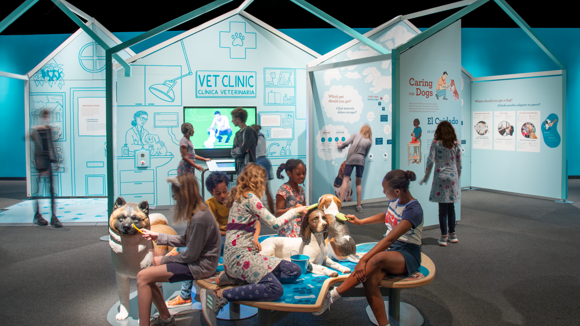 Children interact with veterinary clinic exhibit, brushing and examining large model dogs.