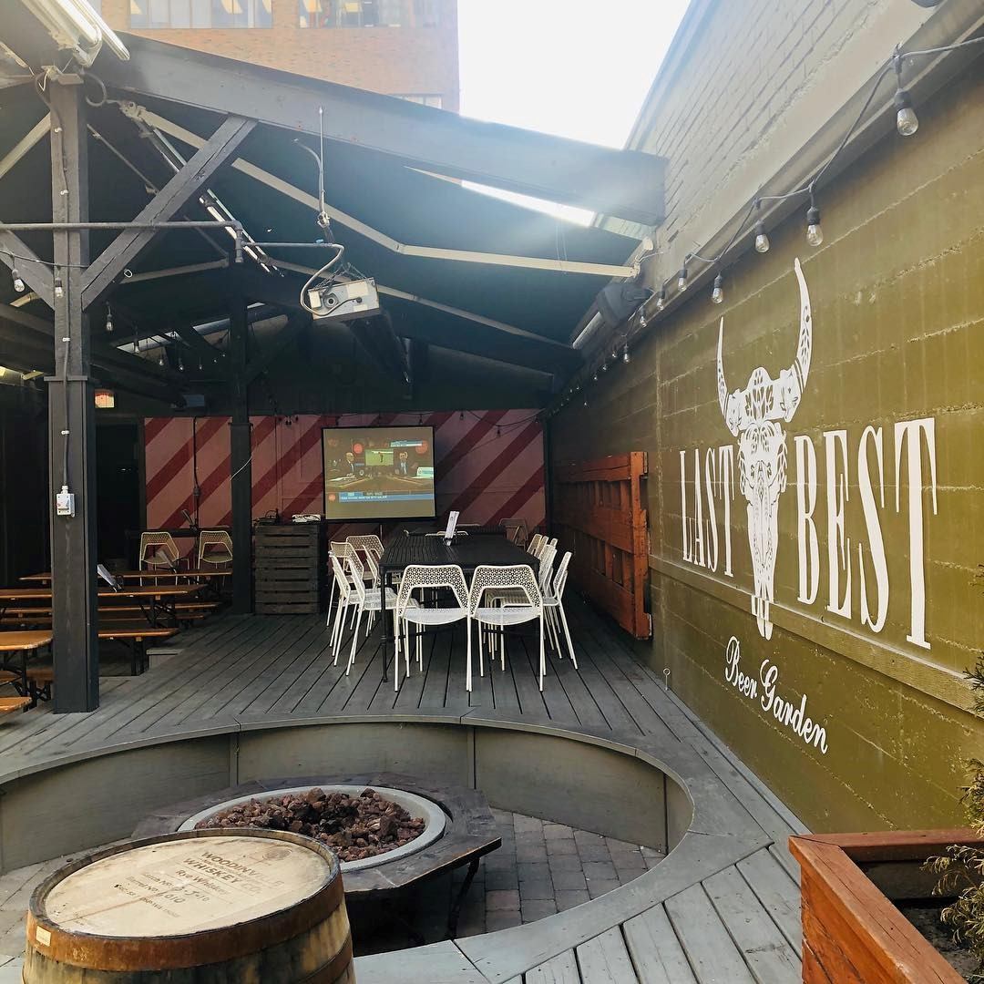 Covered patio with tables, fire pit and wall mural reading Last Best.