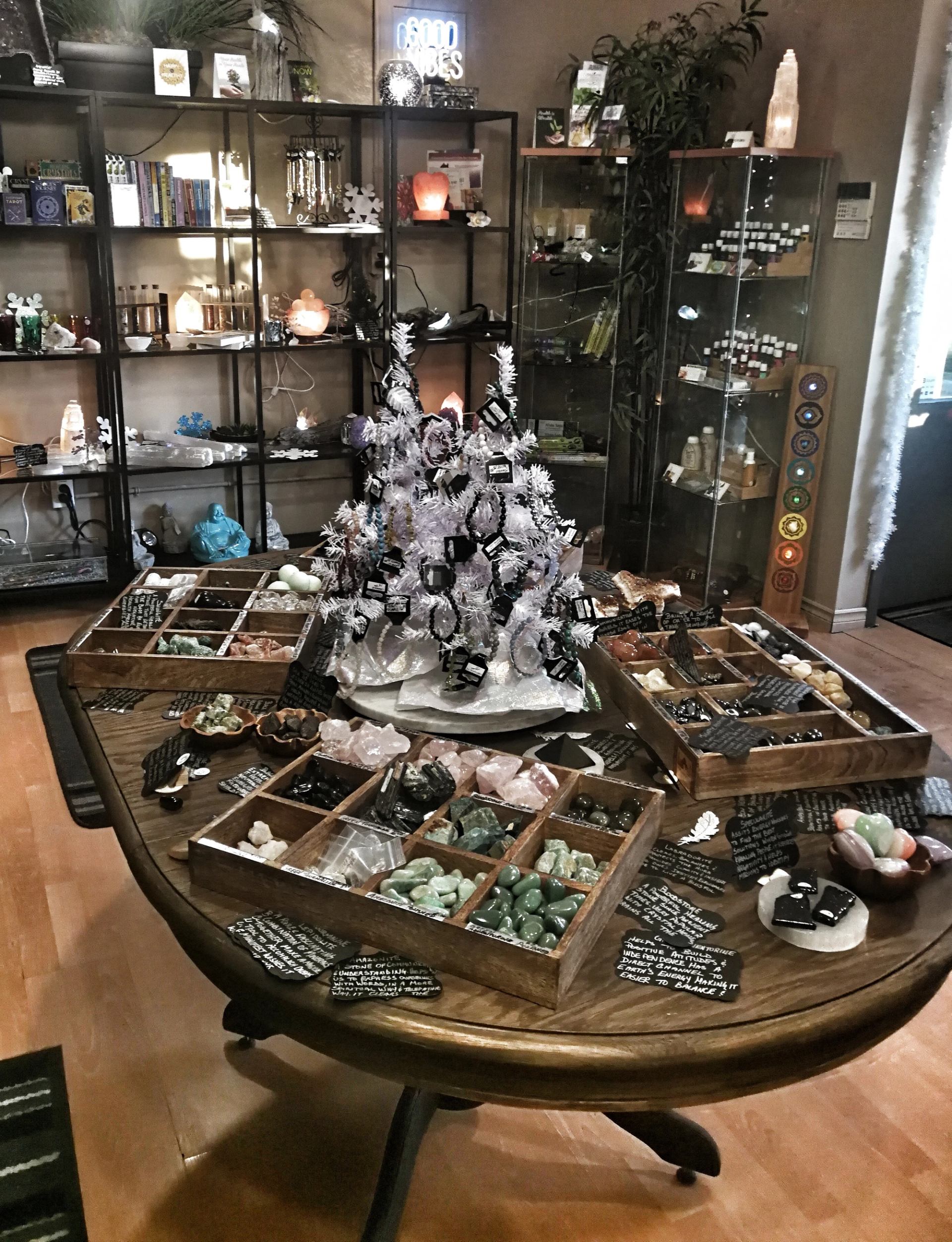 A round table displaying crystals, gemstones, and labeled spiritual items in a boutique.
