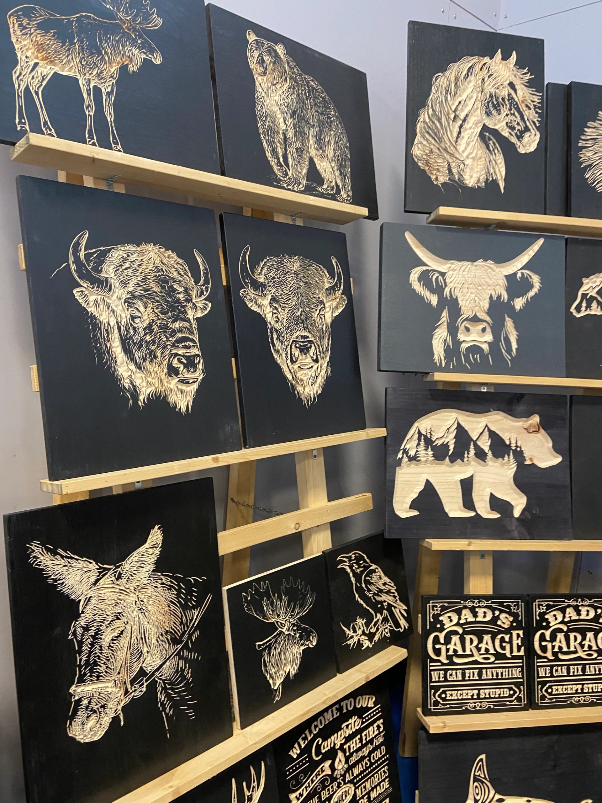 Display of rustic animal-themed wood art and signs at a holiday market.