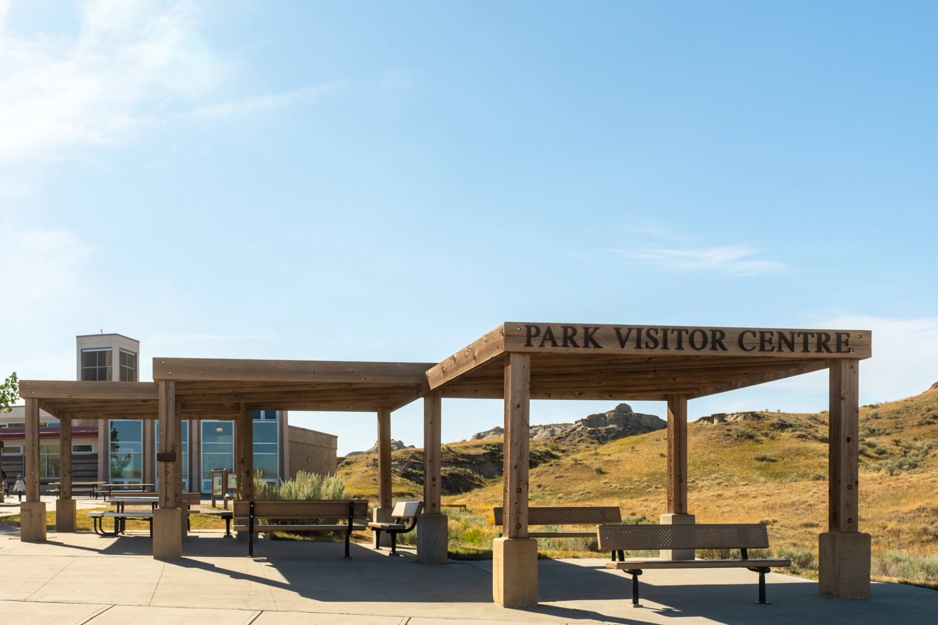 Park visitor centre shelter with benches beside a dry, rocky hillside.