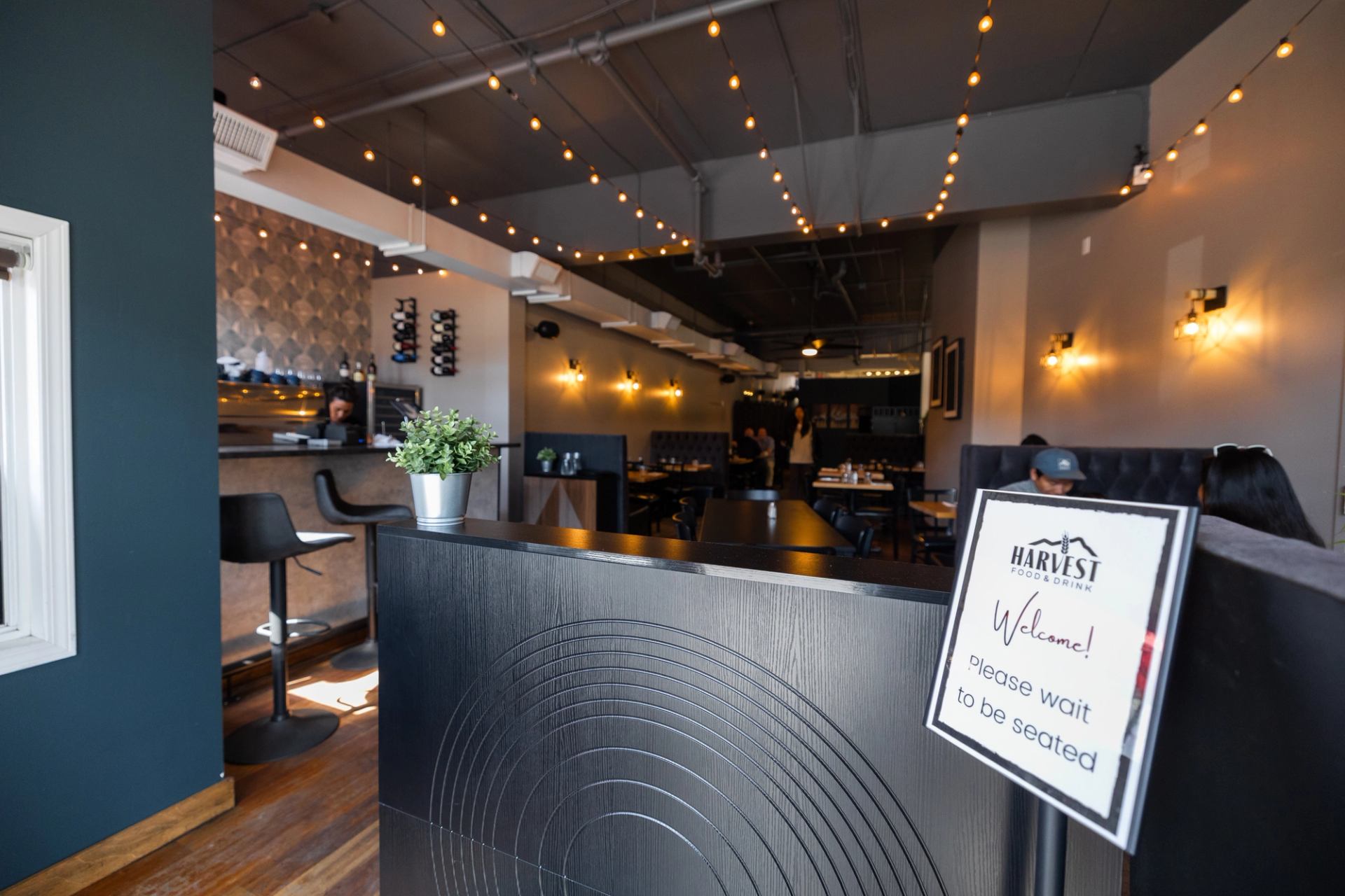 Interior of Harvest Food and Drink with entrance sign, tables, and warm lighting.