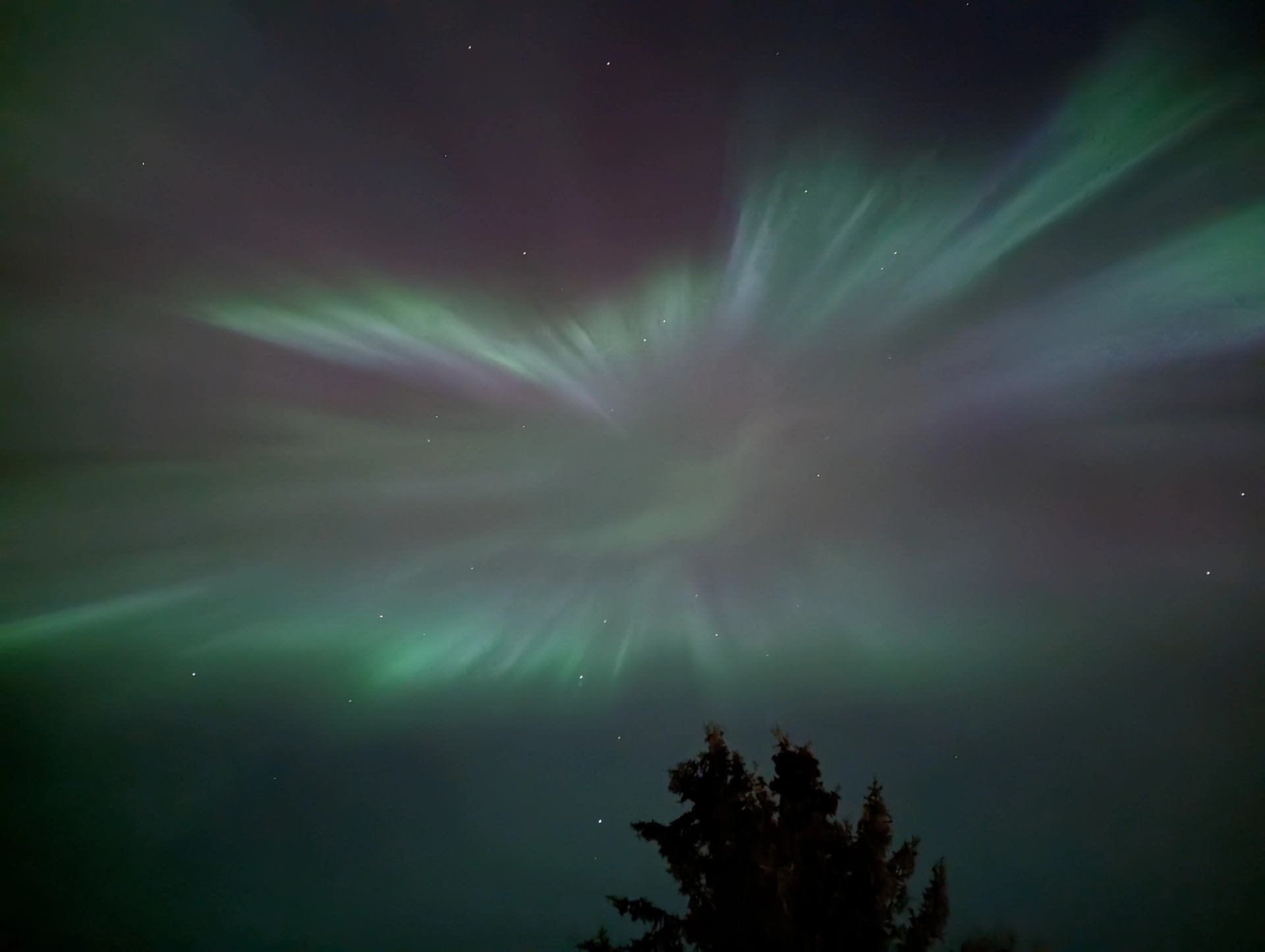 Green and purple northern lights streak across the night sky.