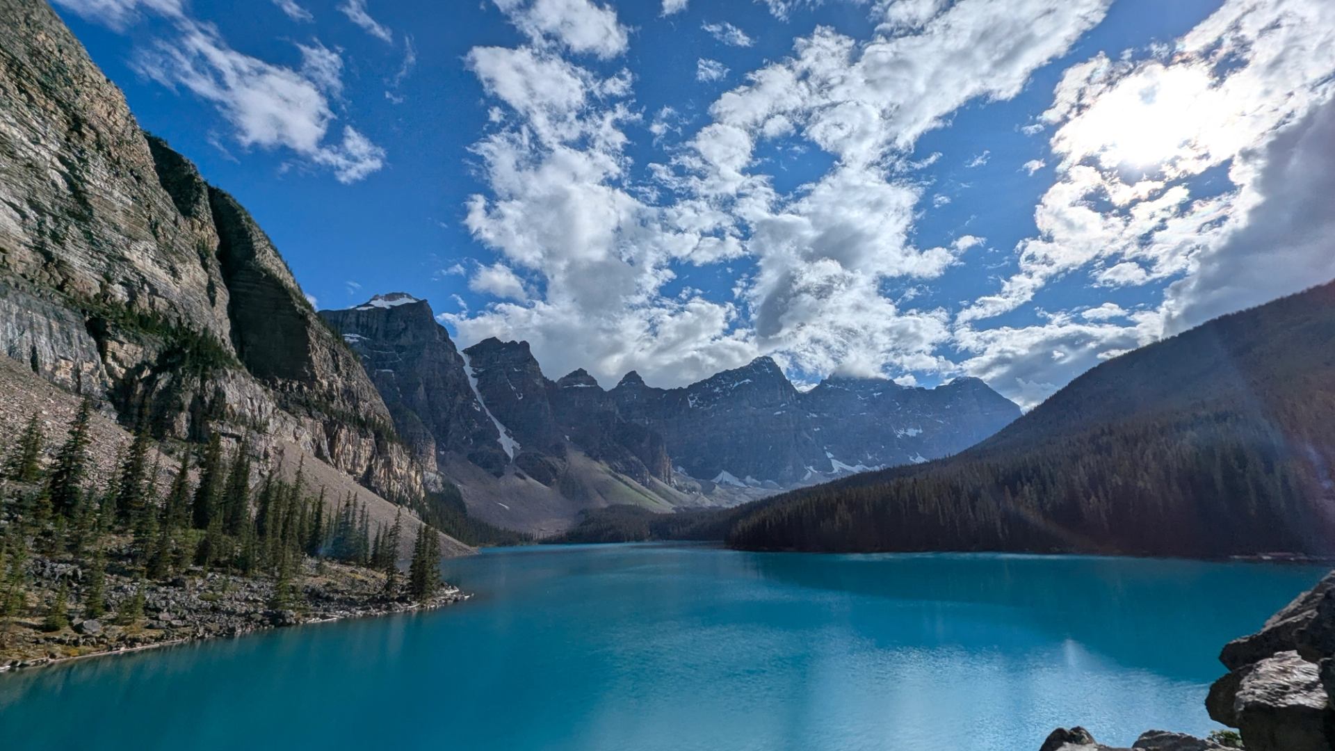 Turquoise lake with mountains and clouds.