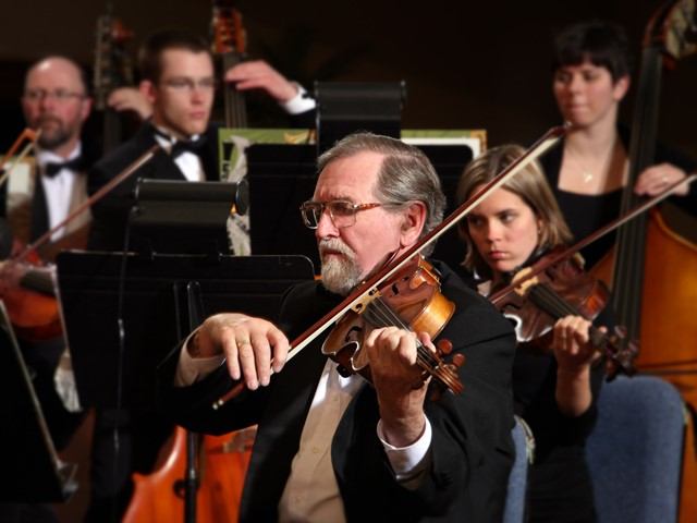 Orchestra members playing the voilin.