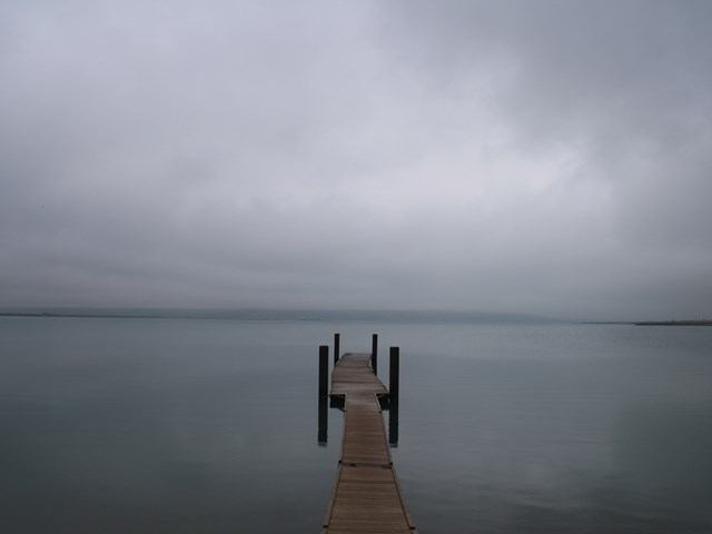 Wooden dock stretching into calm water under cloudy skies at Waterton Reservoir.