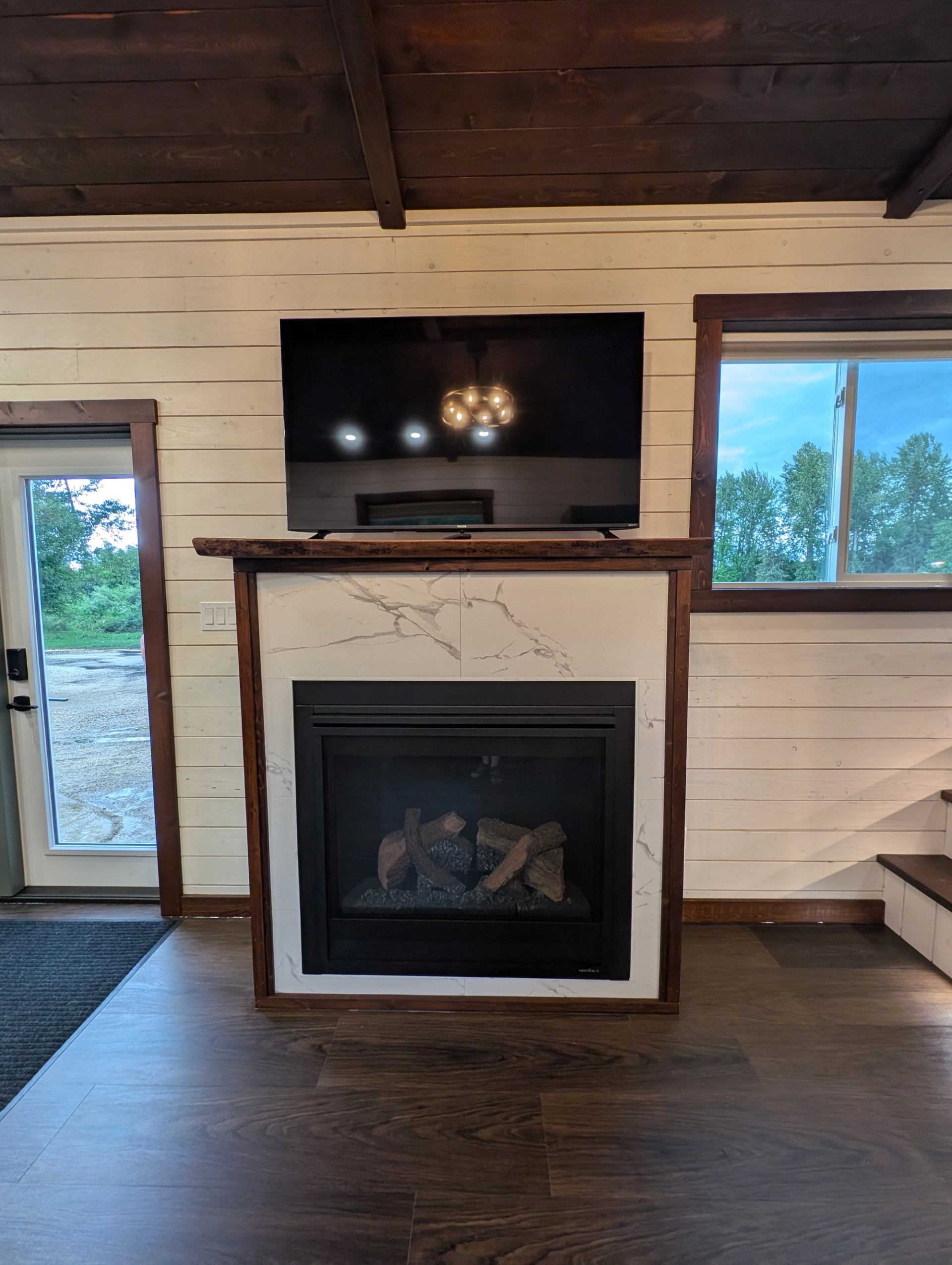 Wall-mounted television above a marble-surround fireplace in a wood-trimmed room.