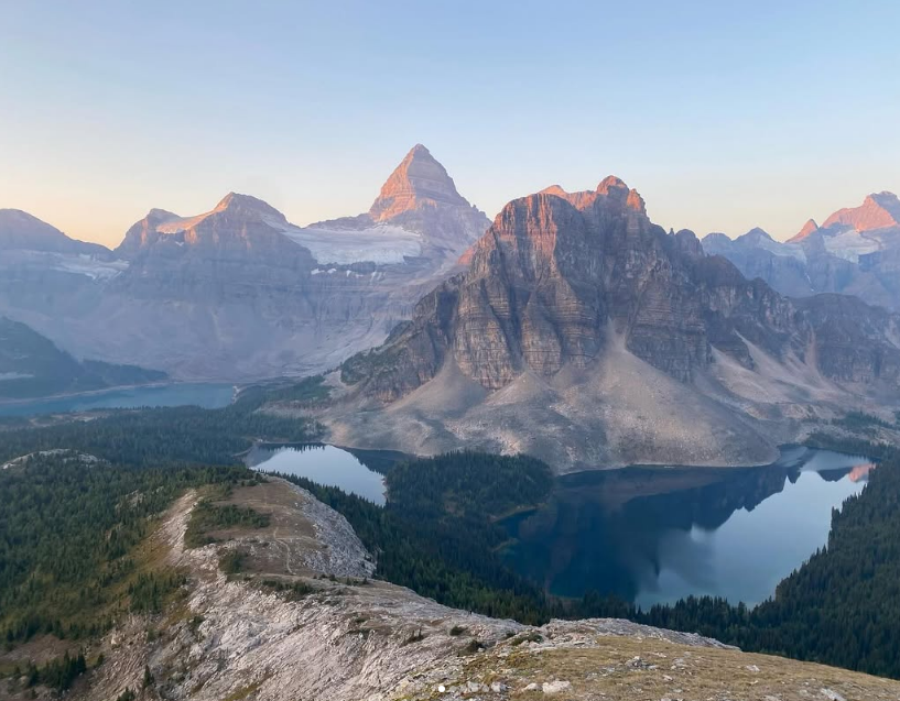 Rocky mountain peaks rise above forested valleys and reflective alpine lakes.