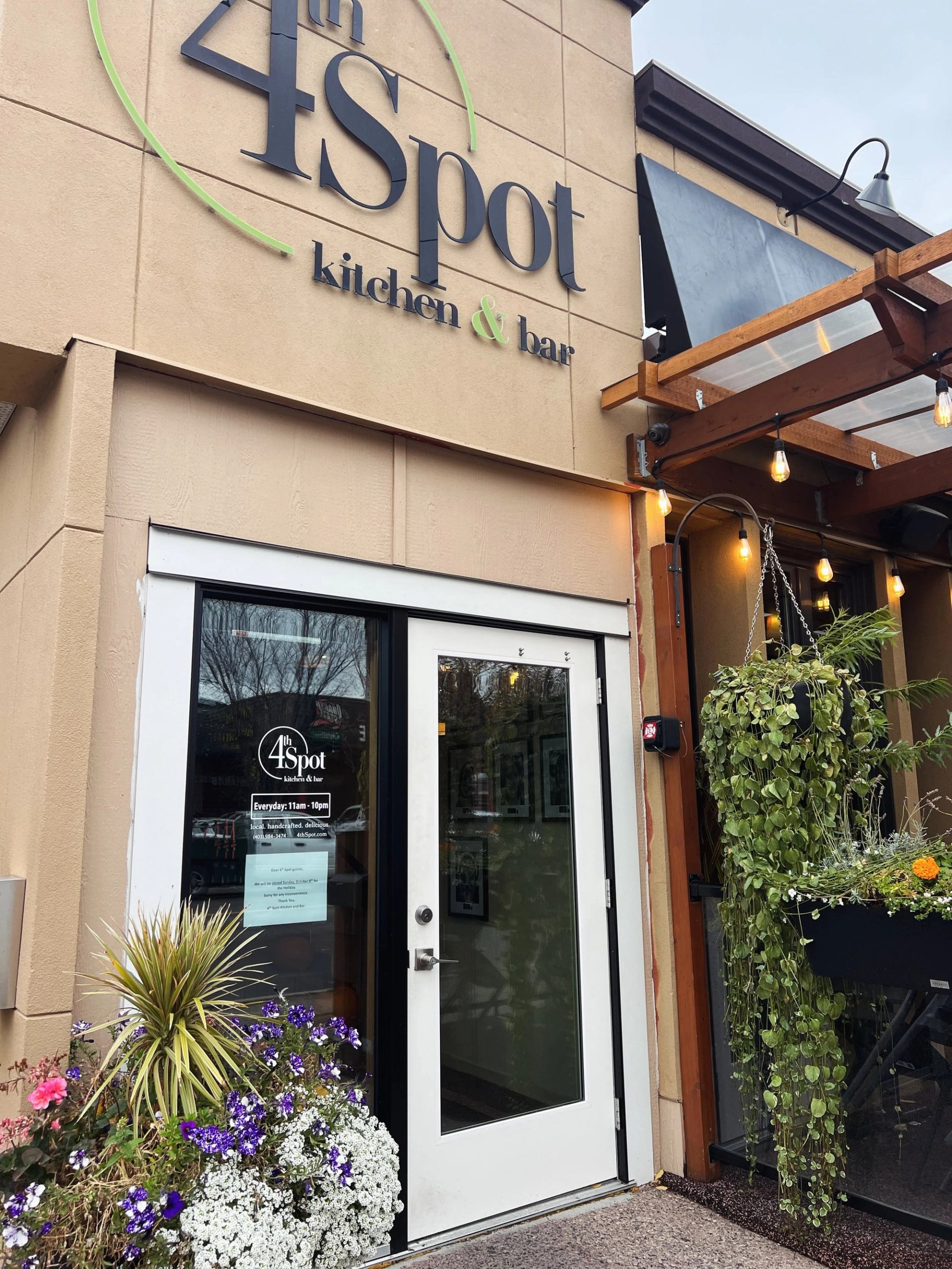 4th Spot kitchen and bar entrance with hanging lights and flower planters.