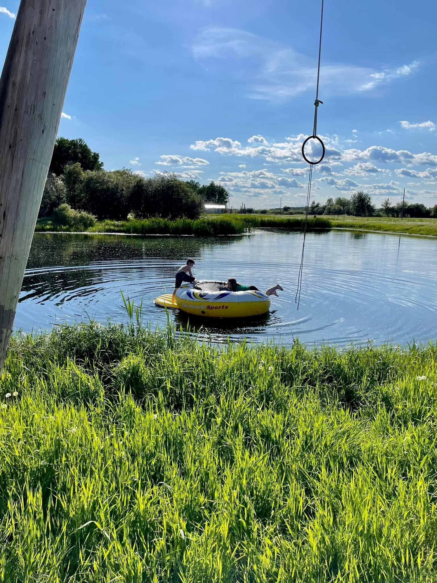 Inflatable raft floating on a calm pond surrounded by green grass