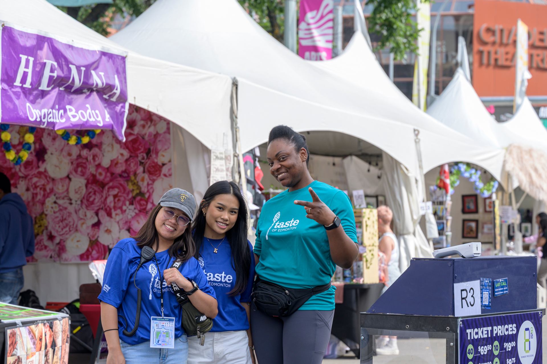 Group posing in front of vendor tents at an outdoor festival.