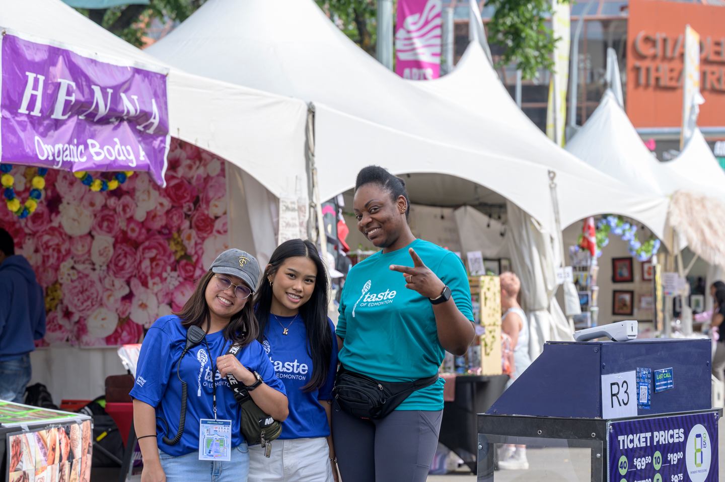 Group posing in front of vendor tents at an outdoor festival.