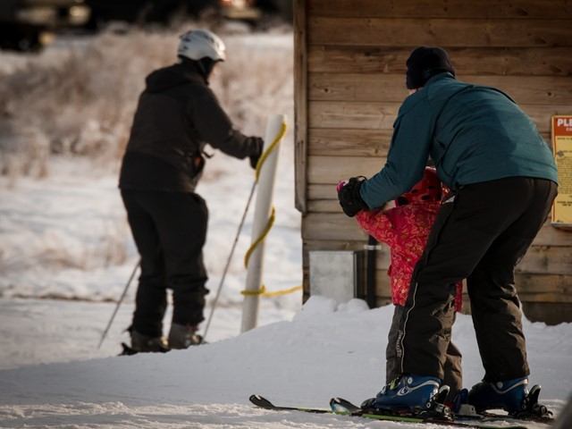 A man teaching a small child to ski