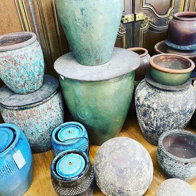 Ceramic vases and pots in varied colours on display shelves.