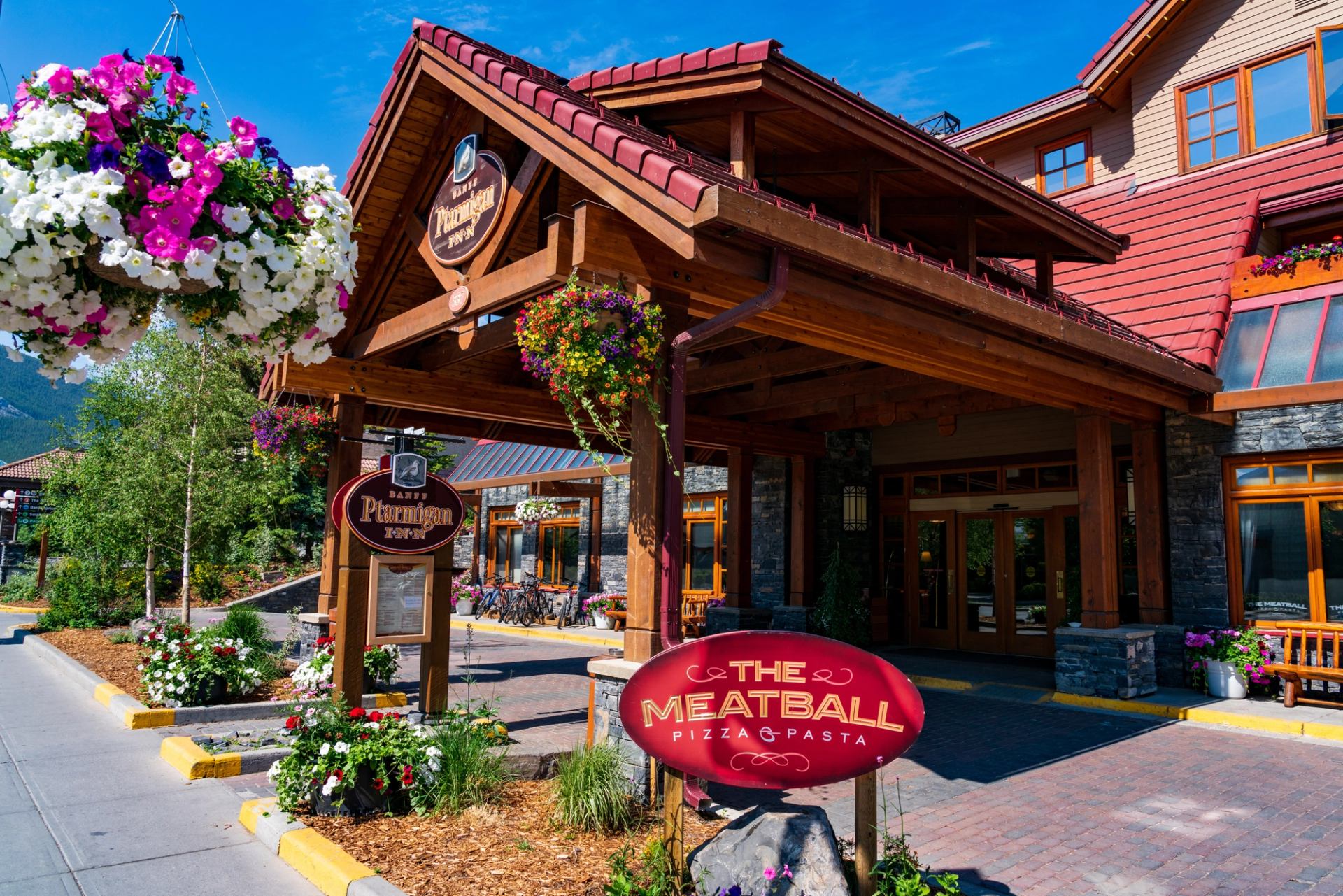Rustic restaurant exterior with wood beams, red roof, and floral decor.