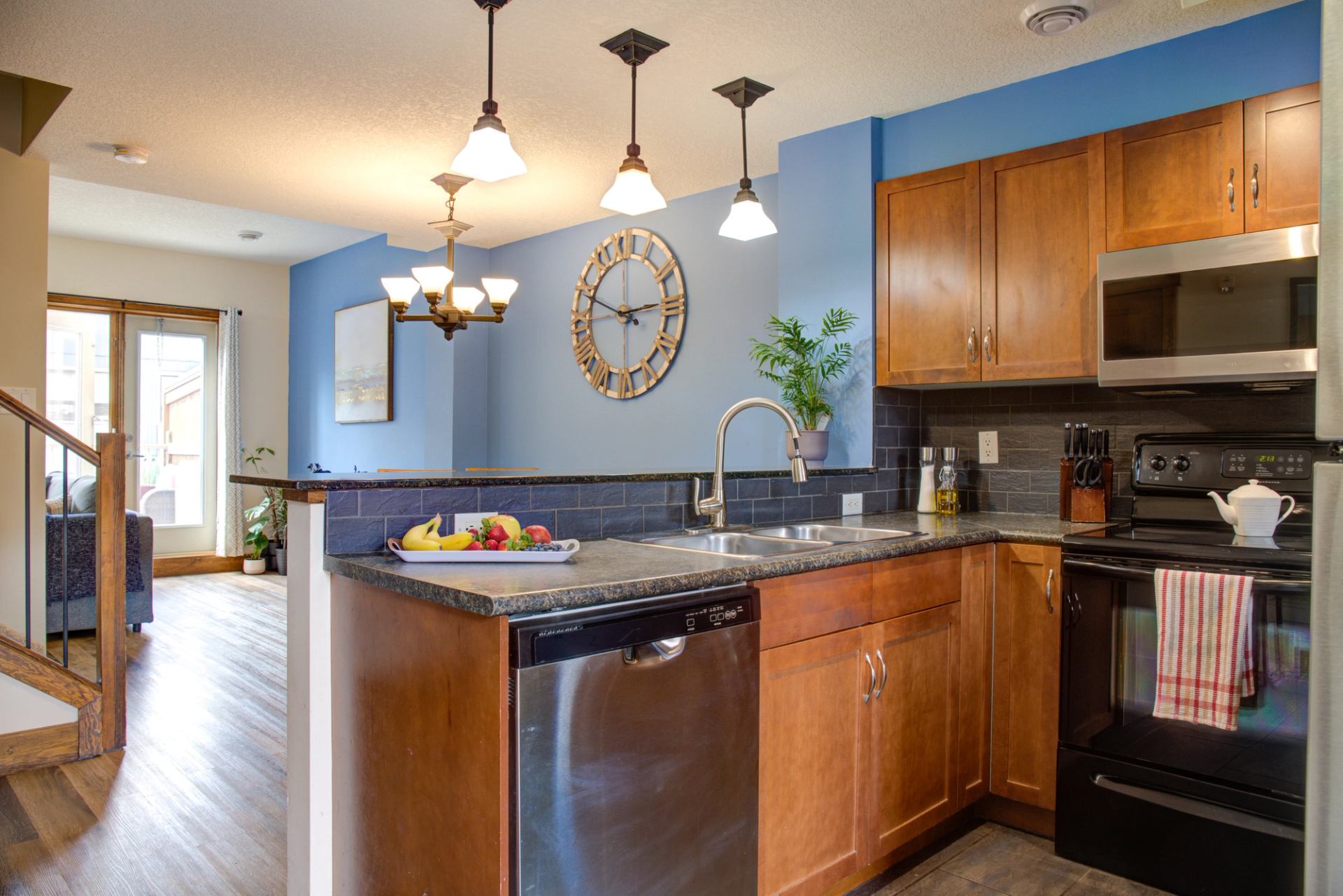 Kitchen with wooden cabinets, island countertop, sink, and hanging light fixtures.