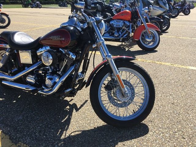 Row of parked motorcycles with chrome engines and blue and red details on street asphalt.