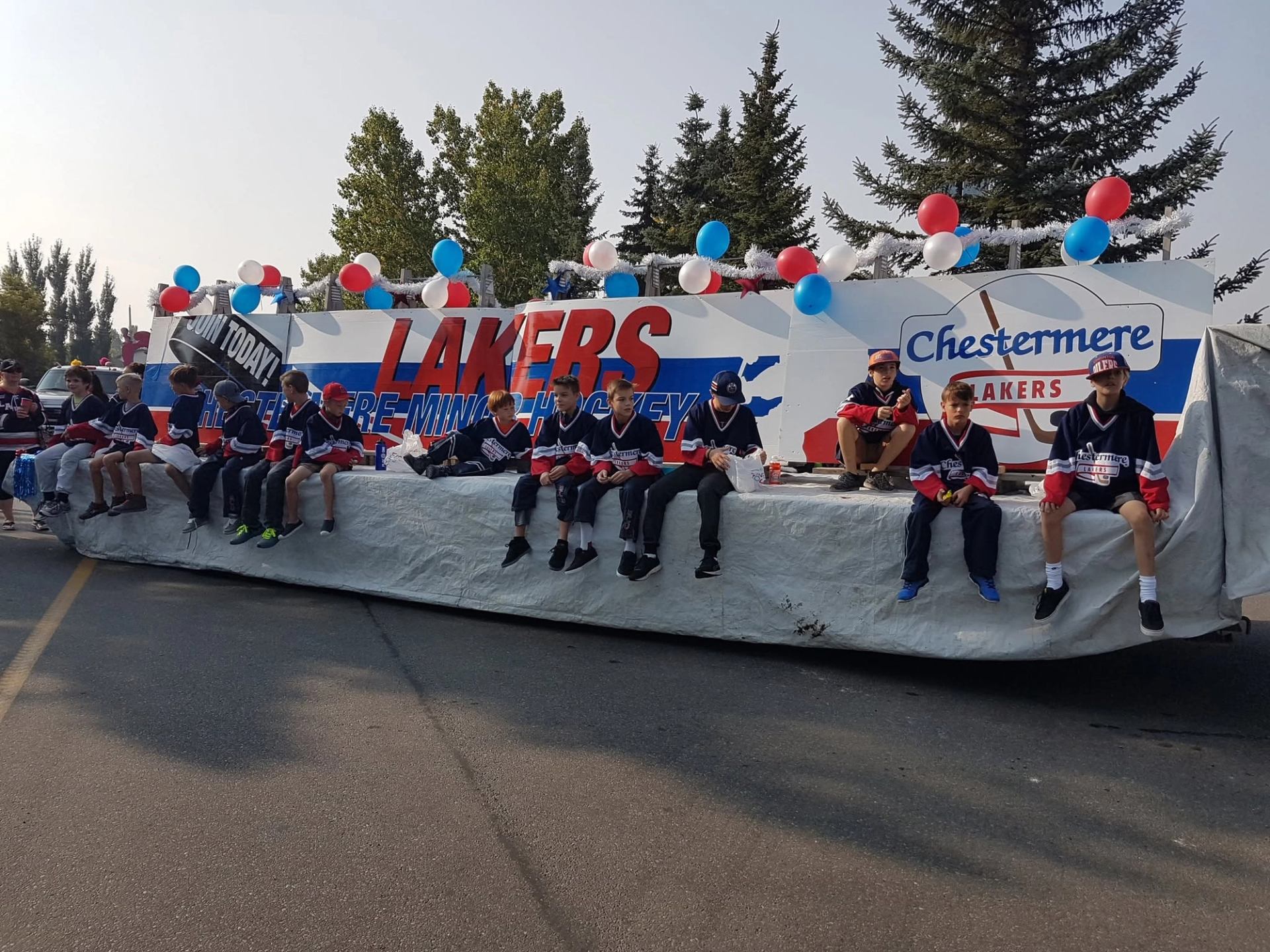 Parade float with Chestermere Lakers youth hockey players in jerseys and balloons.