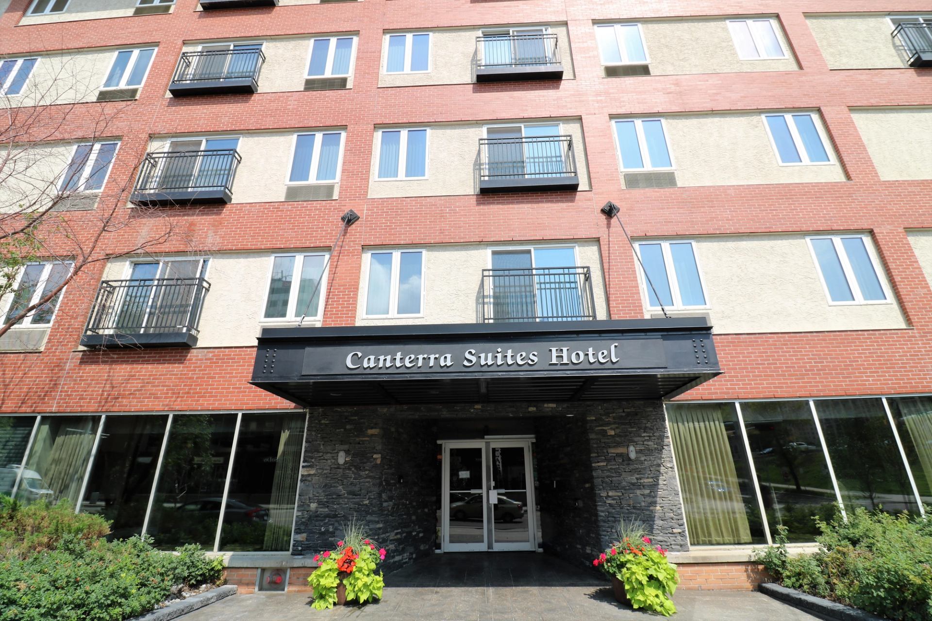 Front entrance of Canterra Suites Hotel with brick exterior and black awning sign.