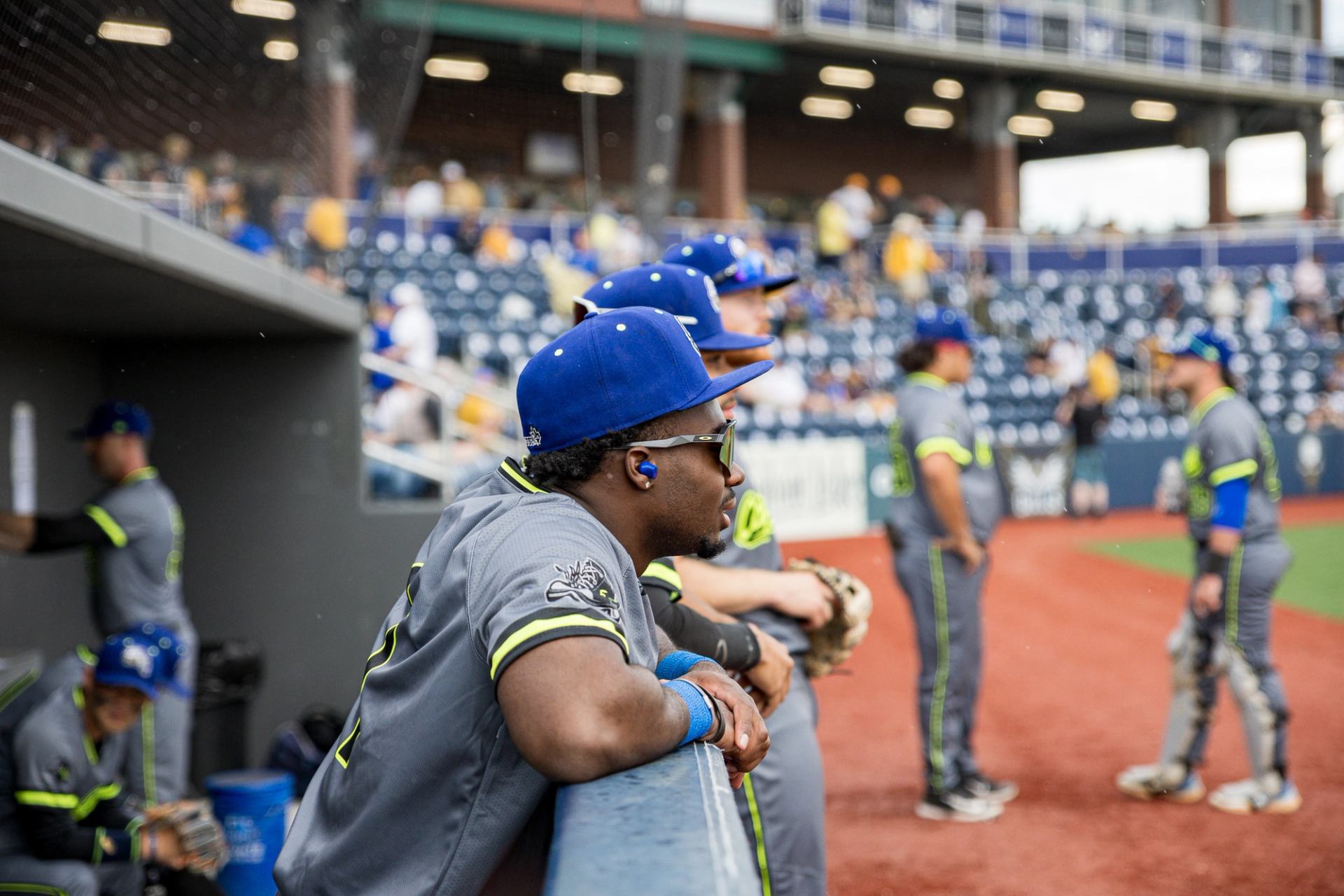 Cactus Rats players in gray uniforms with neon green accents at the dugout.
