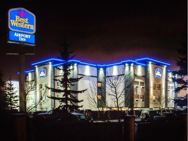 Best Western Airport Inn exterior at night with blue accent lighting.