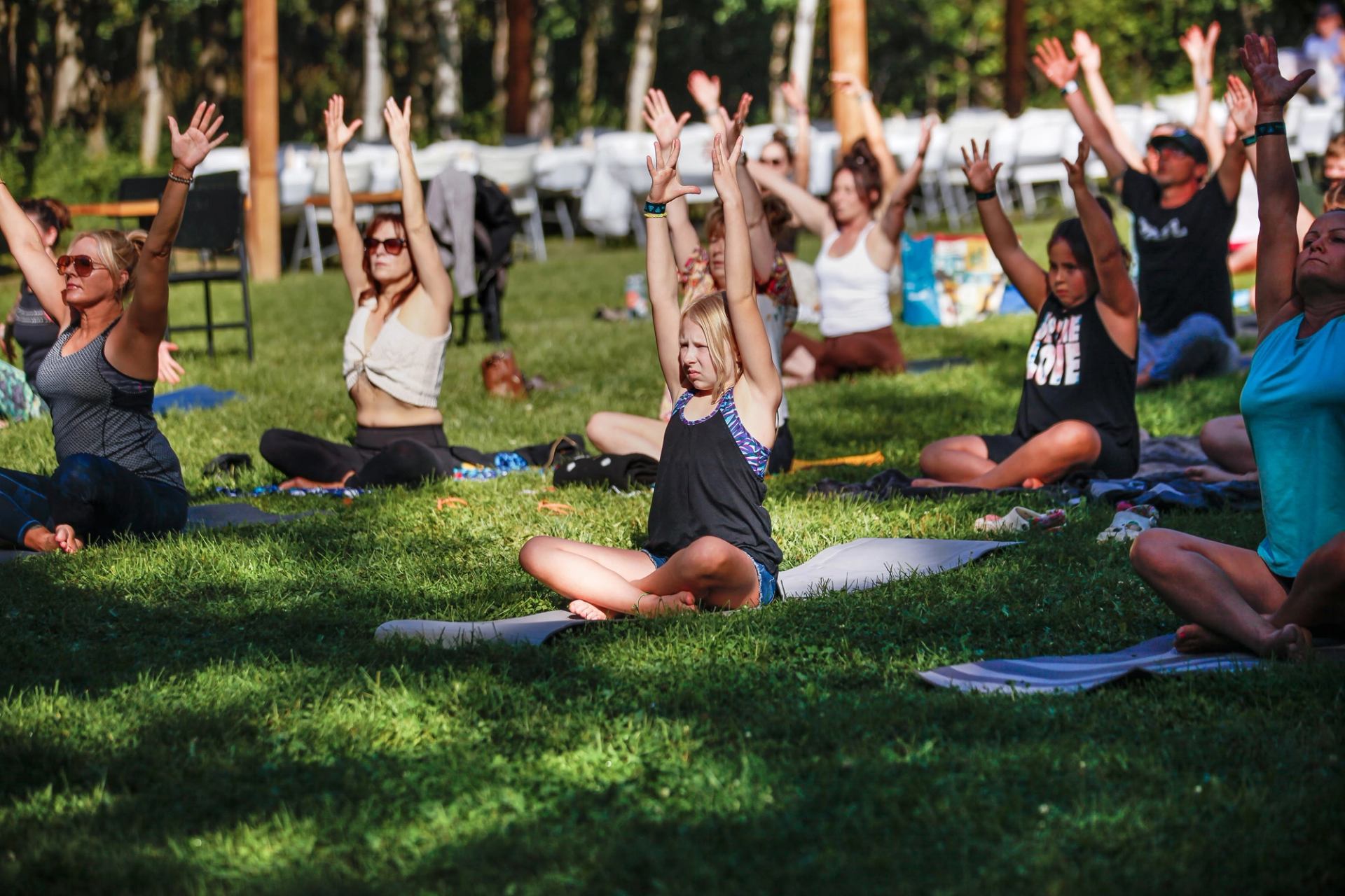 People practicing outdoor yoga together on a grassy lawn during a wellness event.