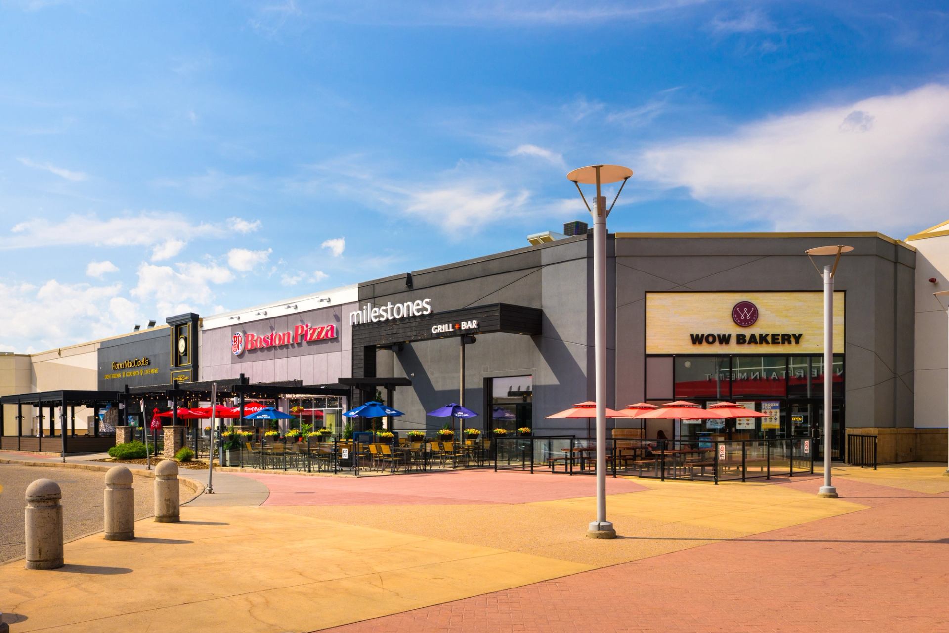 Shops and eateries at CrossIron Mills with outdoor seating and colorful umbrellas.