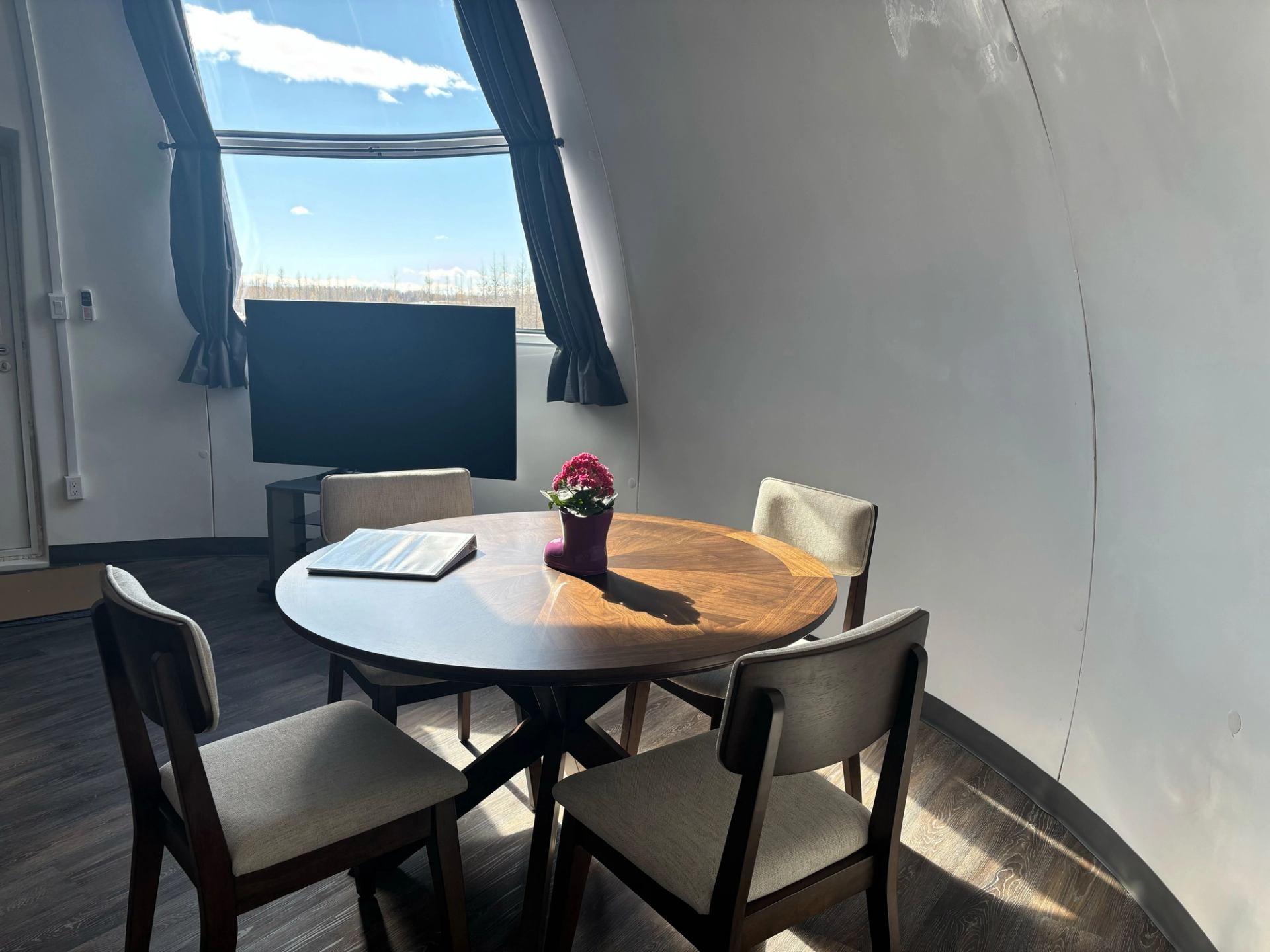 Cozy dome room with round table, chairs, and large window view.