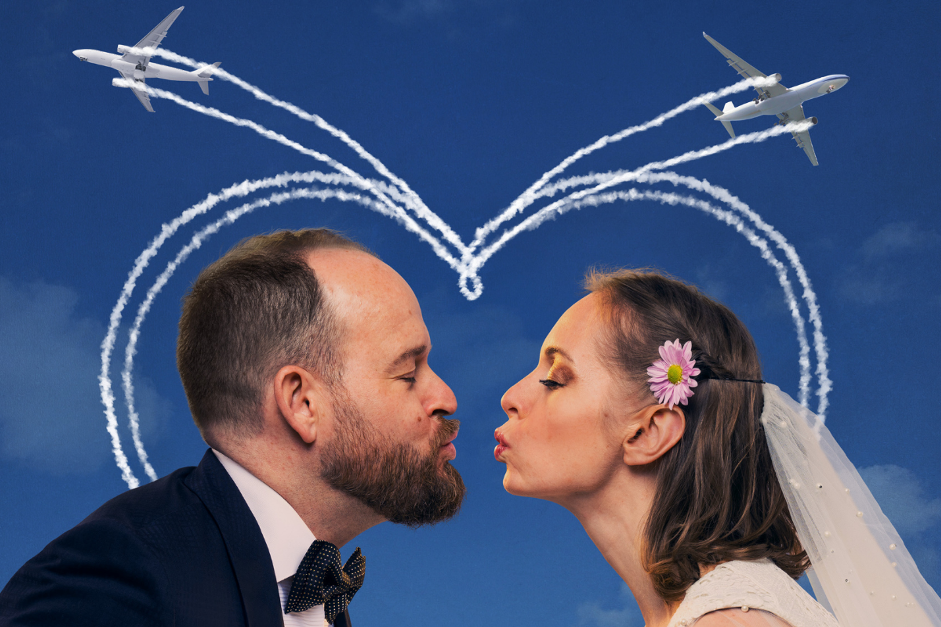 Wedding couple facing each other as two airplanes draw a heart-shaped trail overhead.