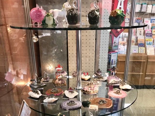 Glass display case with small souvenir items and figurines, and books in background.