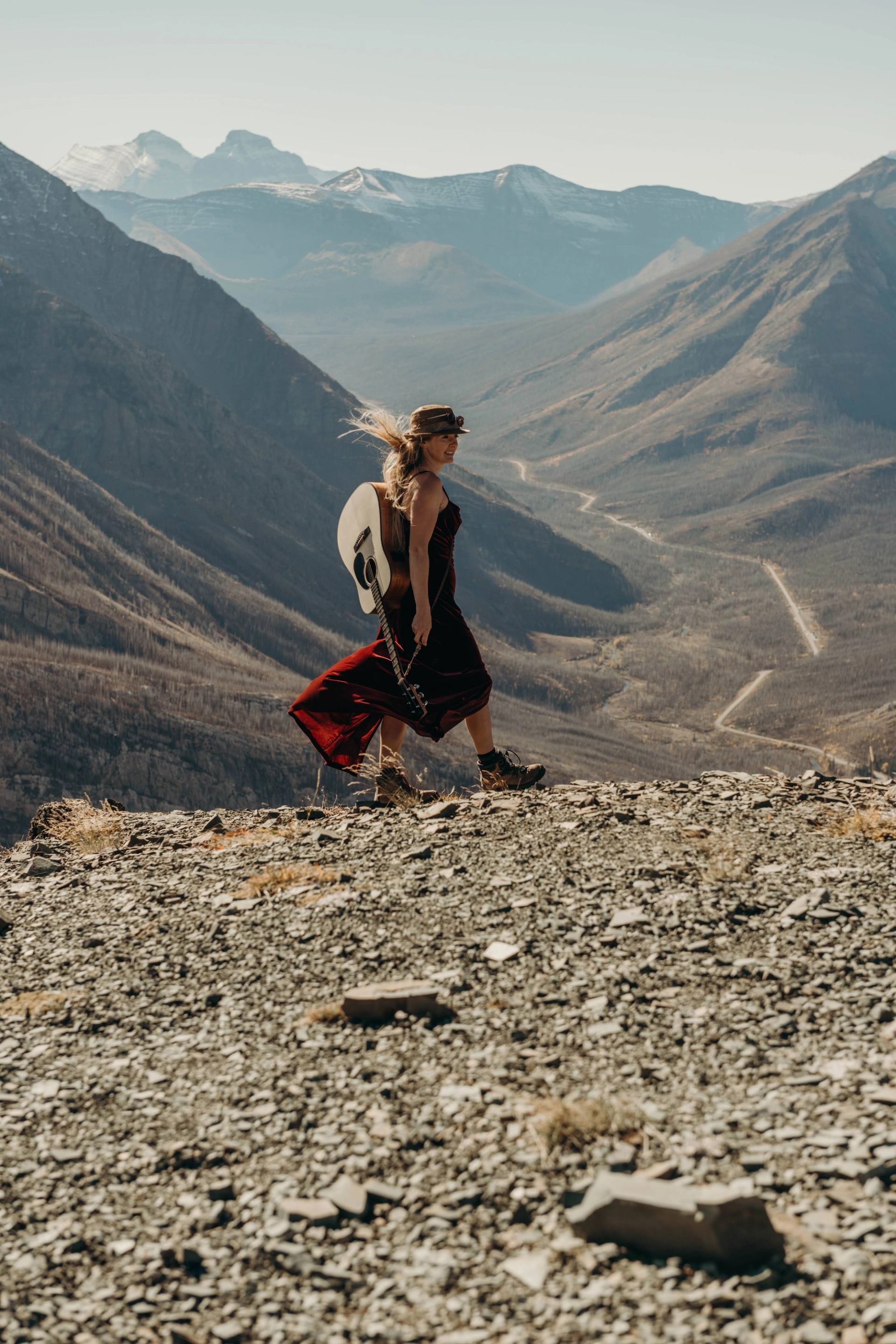 Person walking on rocky terrain with mountains in the background.