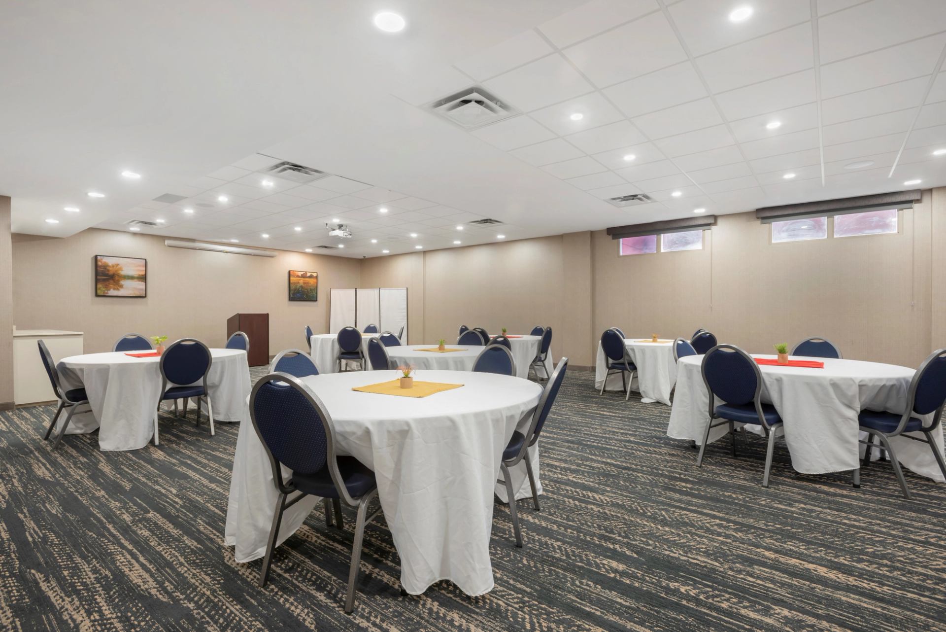 Meeting room with round tables, blue table clothes and patterned carpet.
