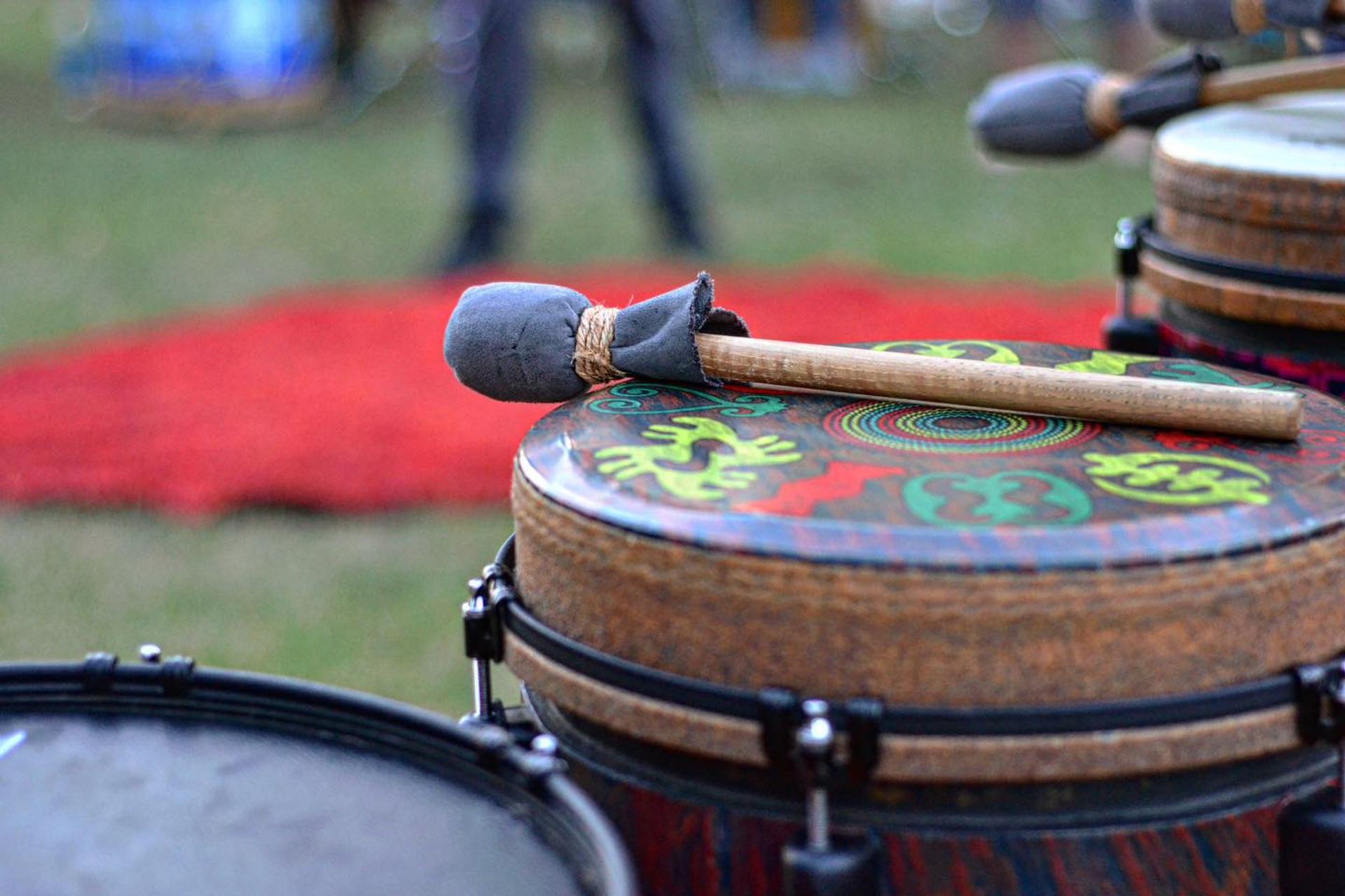 Close-up of hand drums with painted designs and drumsticks resting on top during a Circles of Rhythm event.
