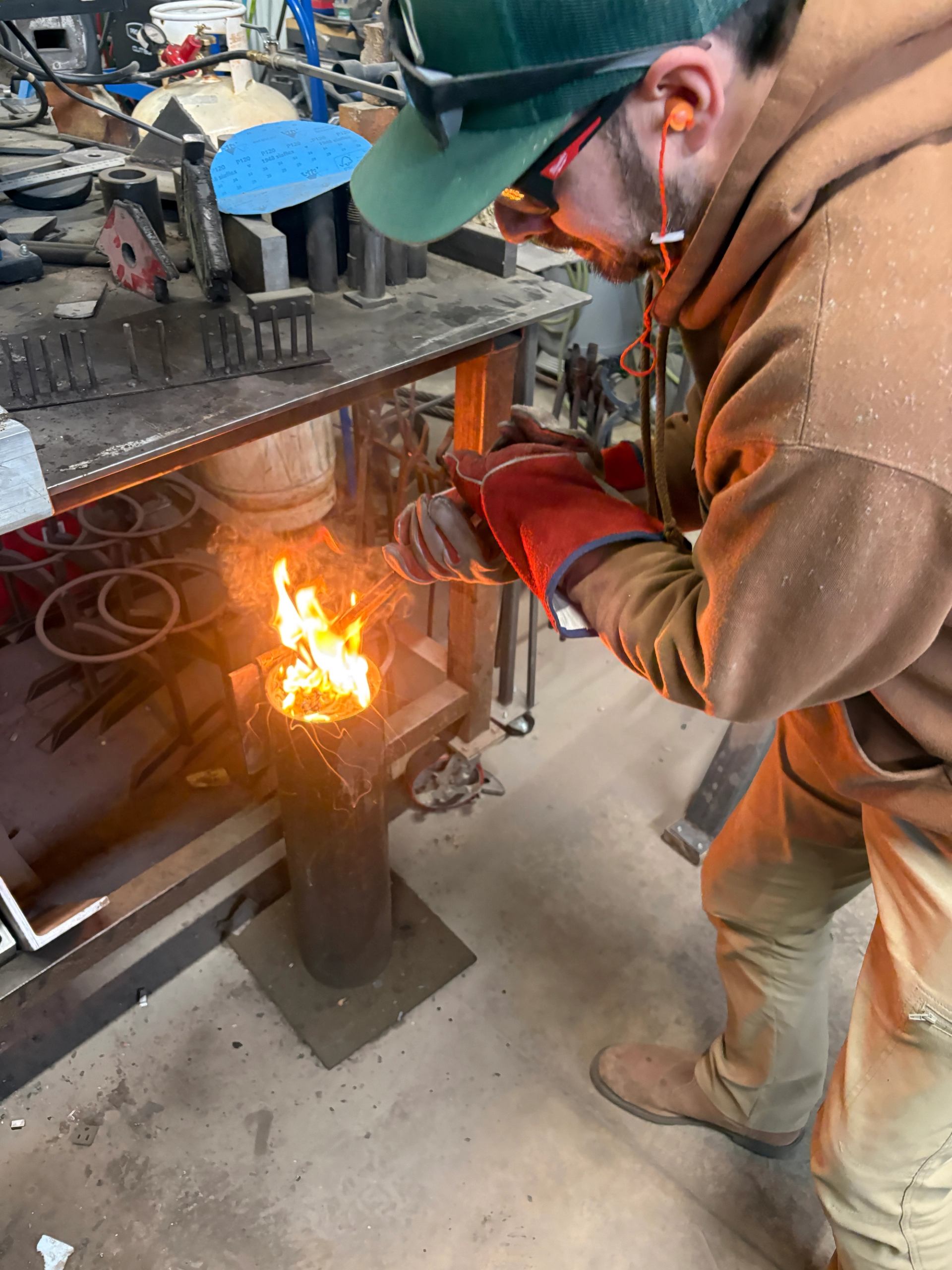 Participant quenching heated steel in a flame during a knife making class. 