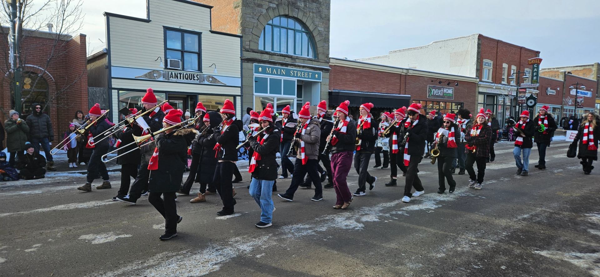 Marching band in Santa hats plays brass instruments in festive street parade.