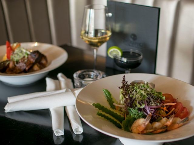 Elegant table with seafood, vegetables, wine, and water garnished with lime.