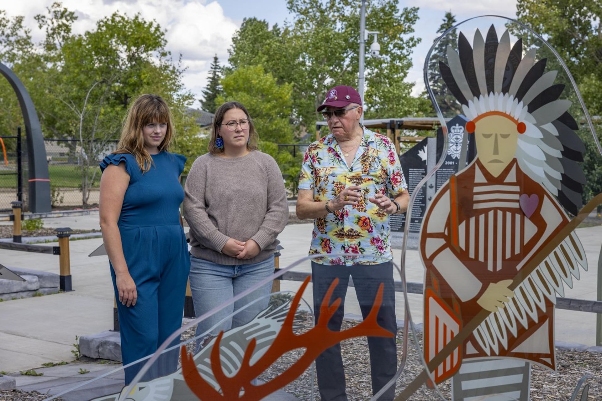 Invisible, a glass war memorial is being viewed by and elder and two female guests