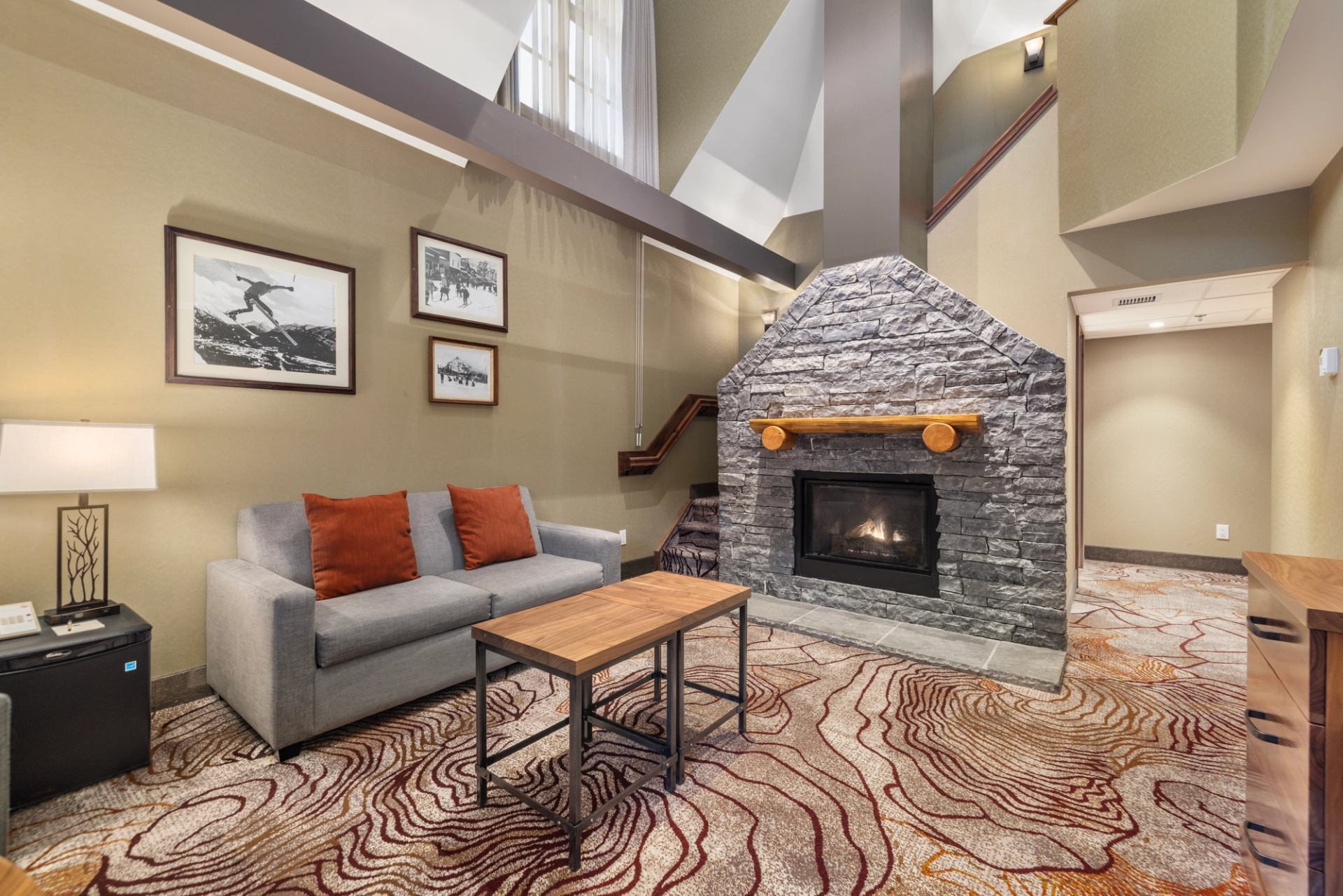Living area with large fireplace made of stone, small couch and coffee table.